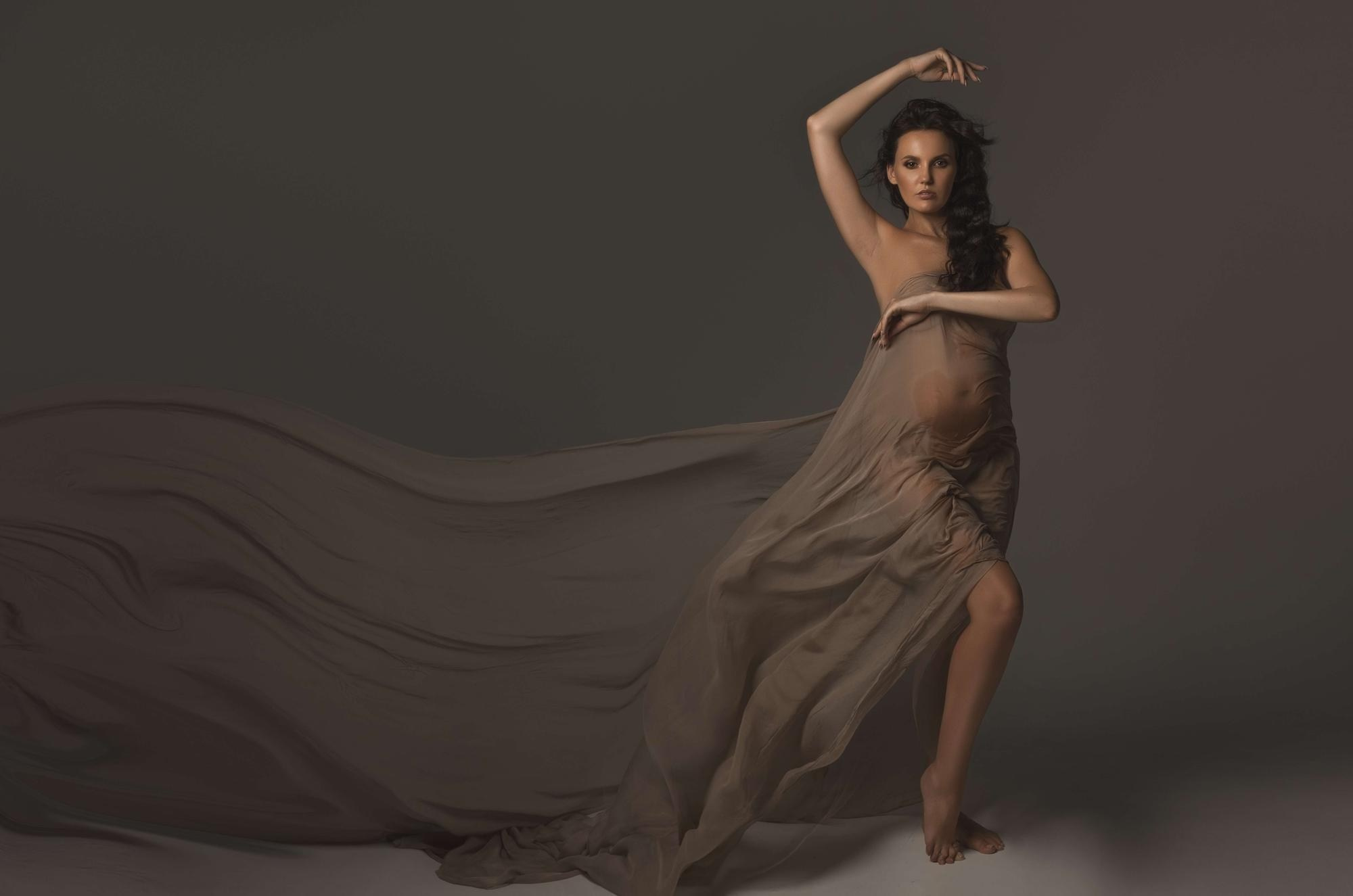 фотосессия беременной в фотостудии на темном фоне в красивом разлетающемся платье, фотография беременности, фотосессия беременных, портрет беременной