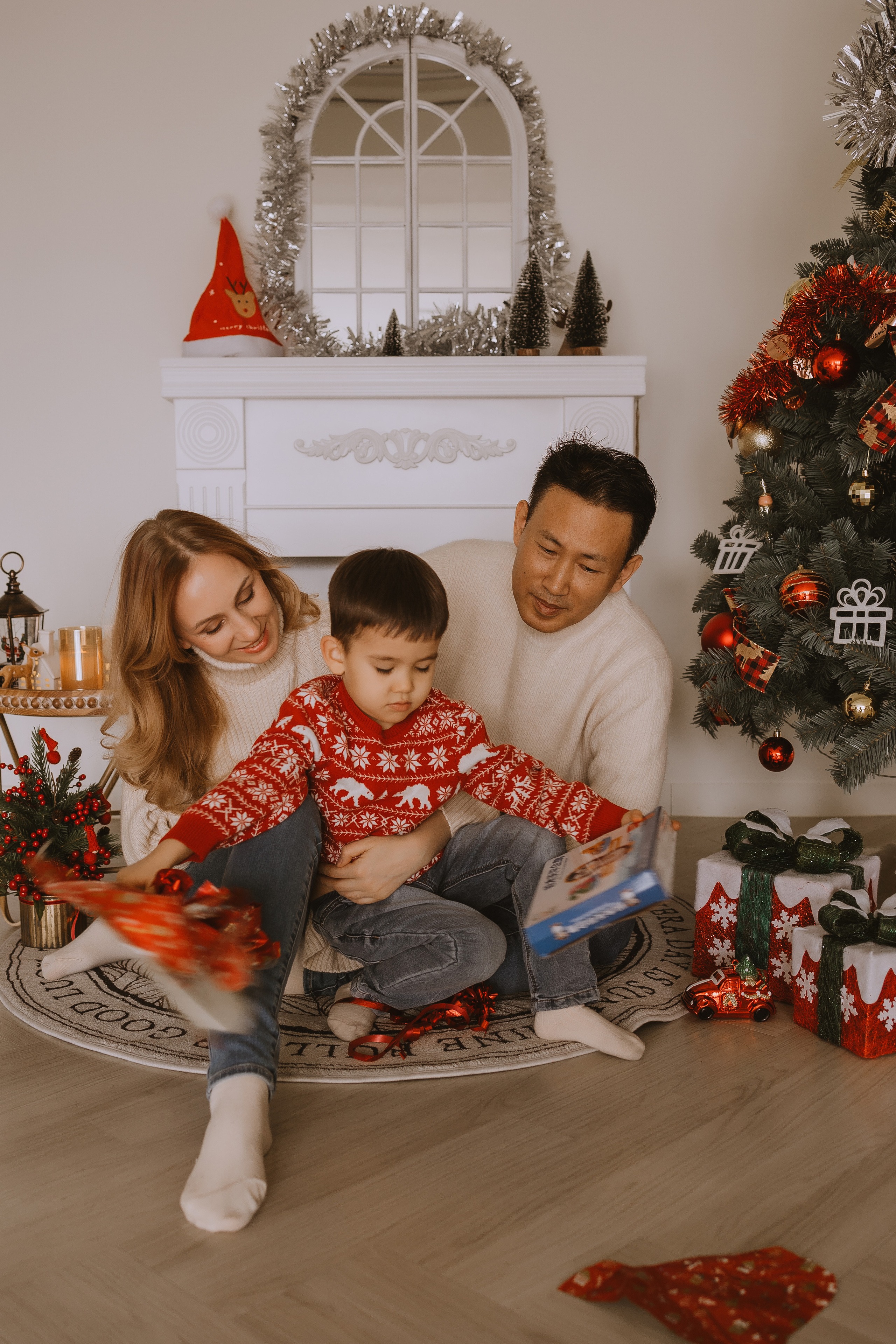 Семья у камина под елкой открывает новогодние подарки