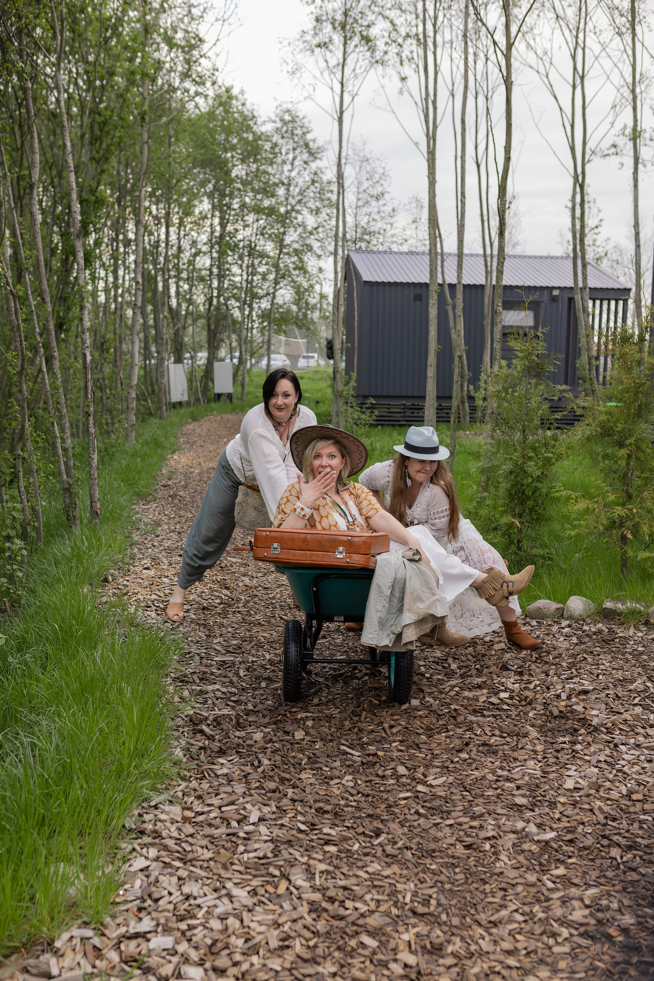 Девочки катают друг друга в садовой тачке, смеются и дурачатся