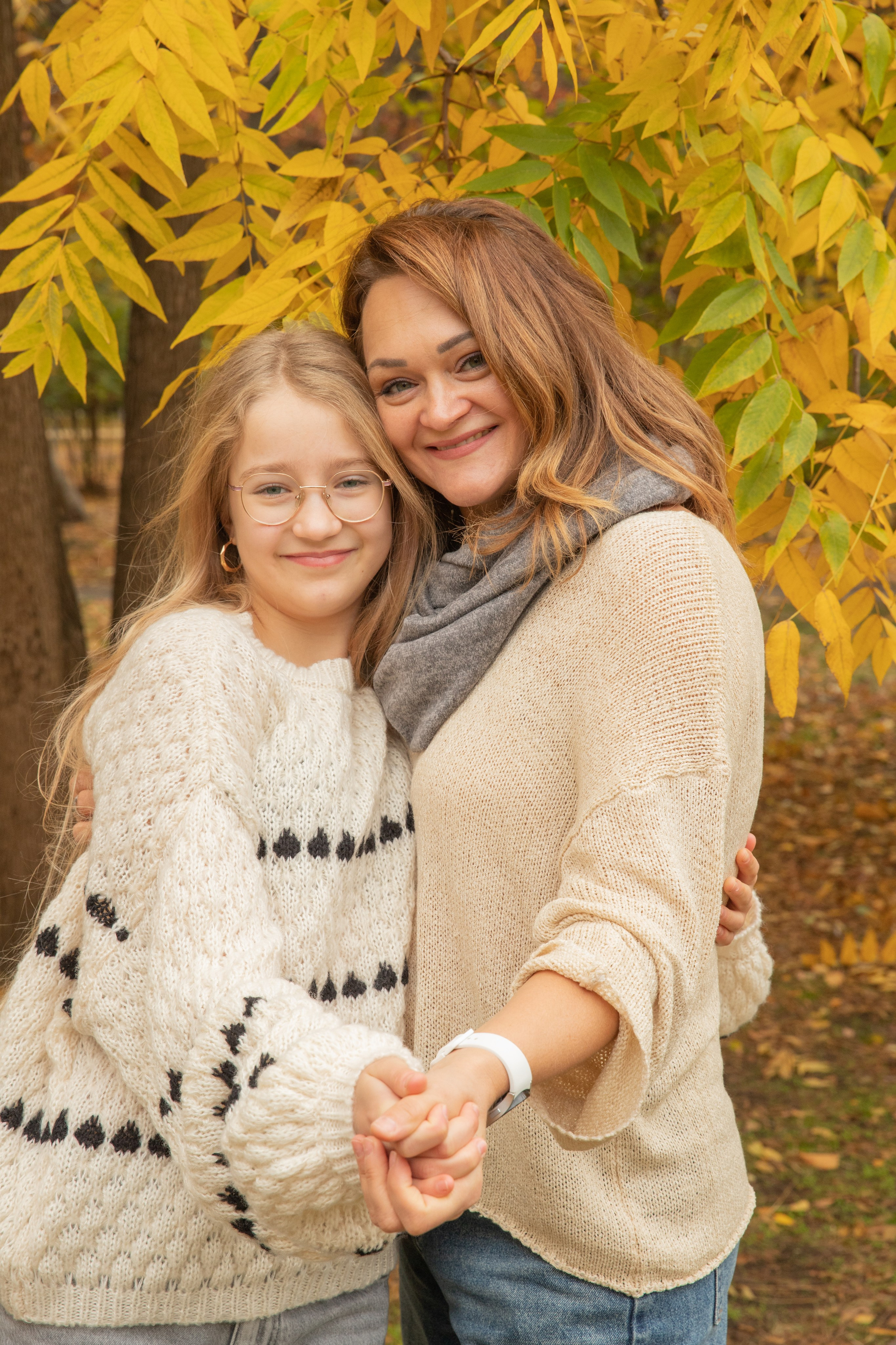 Счастливая мама обнимает дочку на фоне  ярко - желтой  листвы в парке Чистяковская роща осенью.