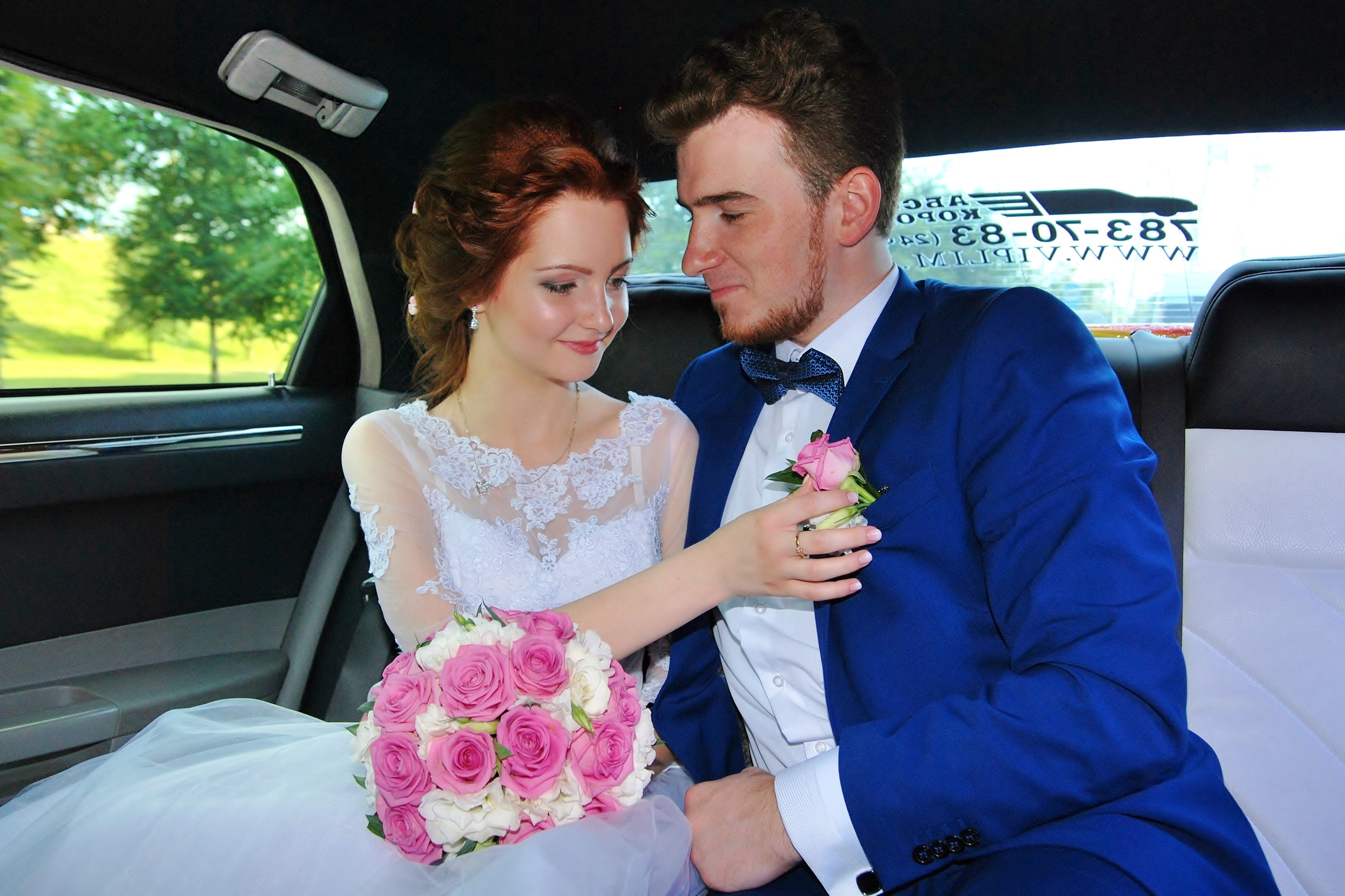 Свадебная фотосъёмка летом, молодожены едут в машине, невеста поправляет бутоньерку жениху