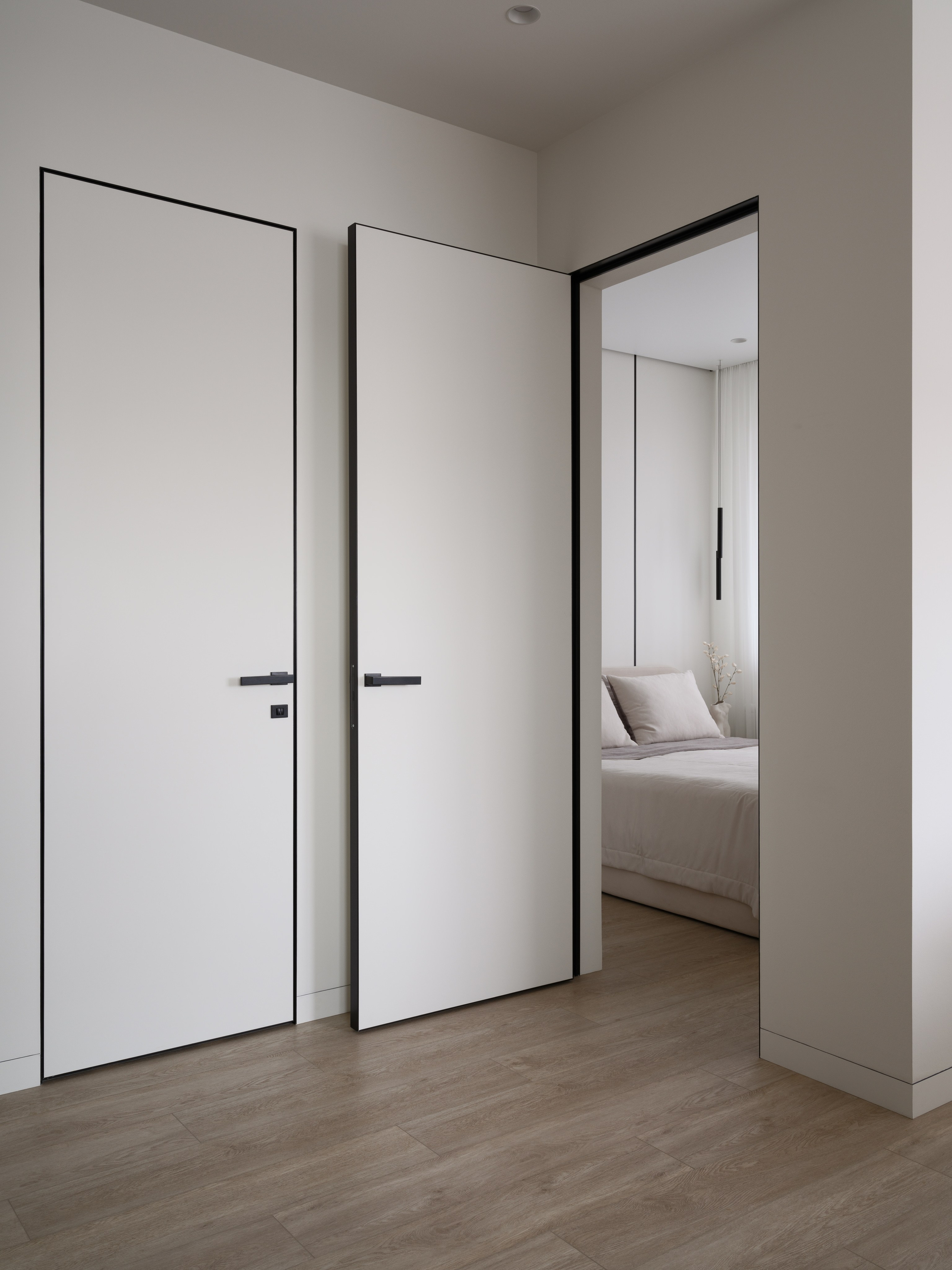 Белые межкомнатные двери с черными ручками в современном минималистичном интерьере спальни. Автор проекта — дизайнеры Евгения Княжева и Владлена Привалова, фотограф Сергей Денисенко