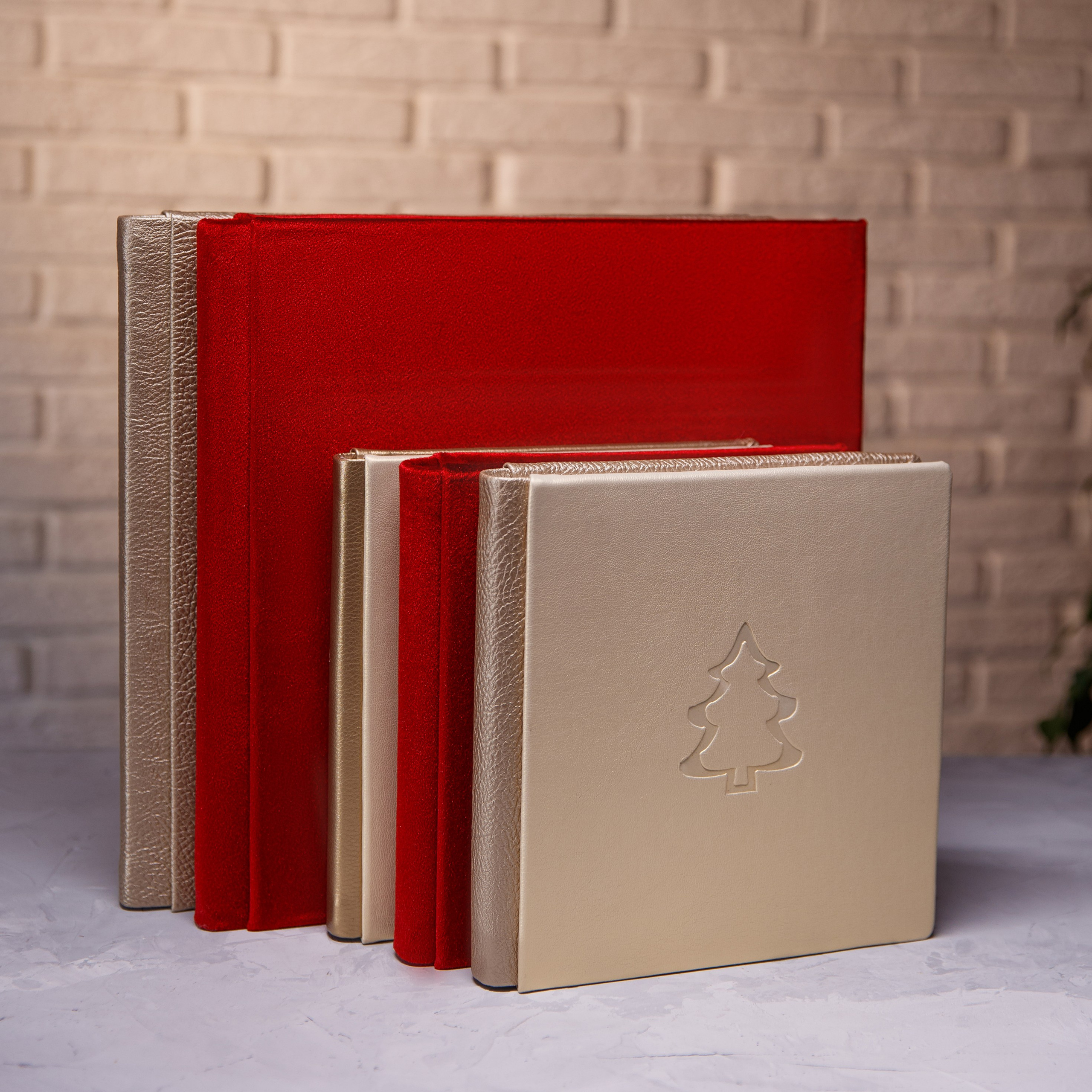 Коллекция фотокниг разных размеров в обложках из красного бархата и золотой экокожи с новогодним тиснением.