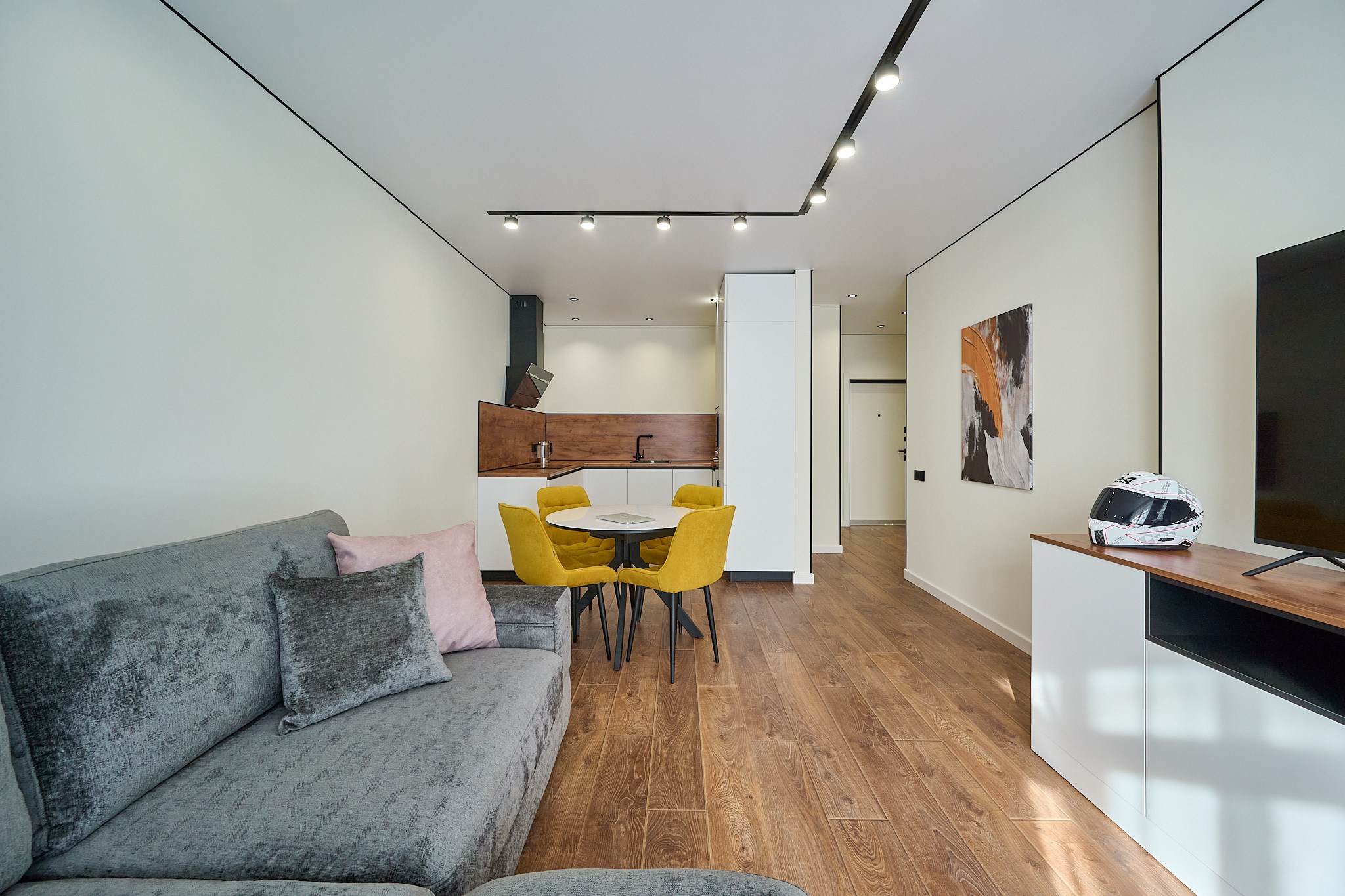 серый диван кухня кухонный стол с желтыми стульями и деревянными белыми шкафами 