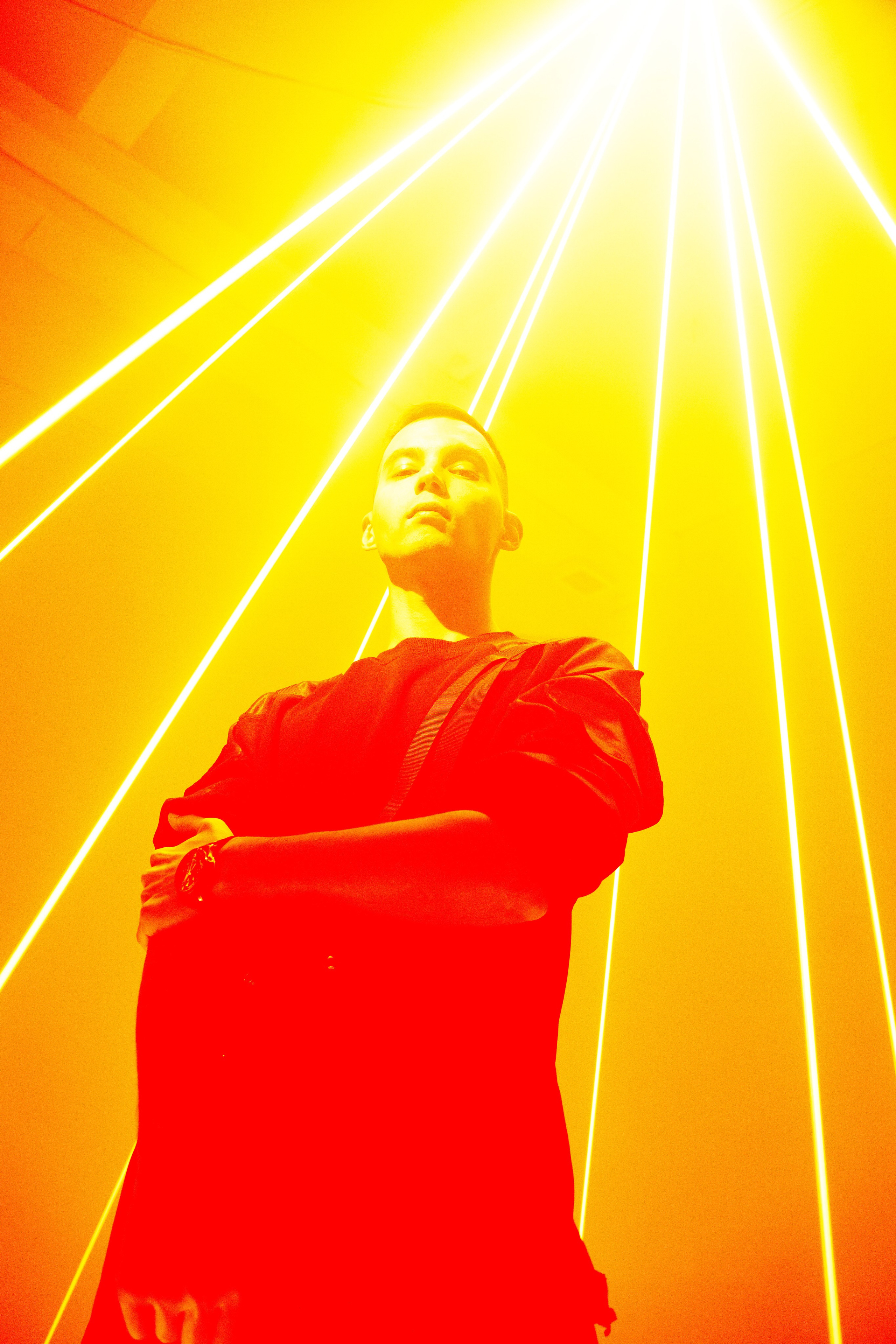 Мужчина стоит под расходящимися лазерными лучами в студии. Стиль бегущий по лезвию.