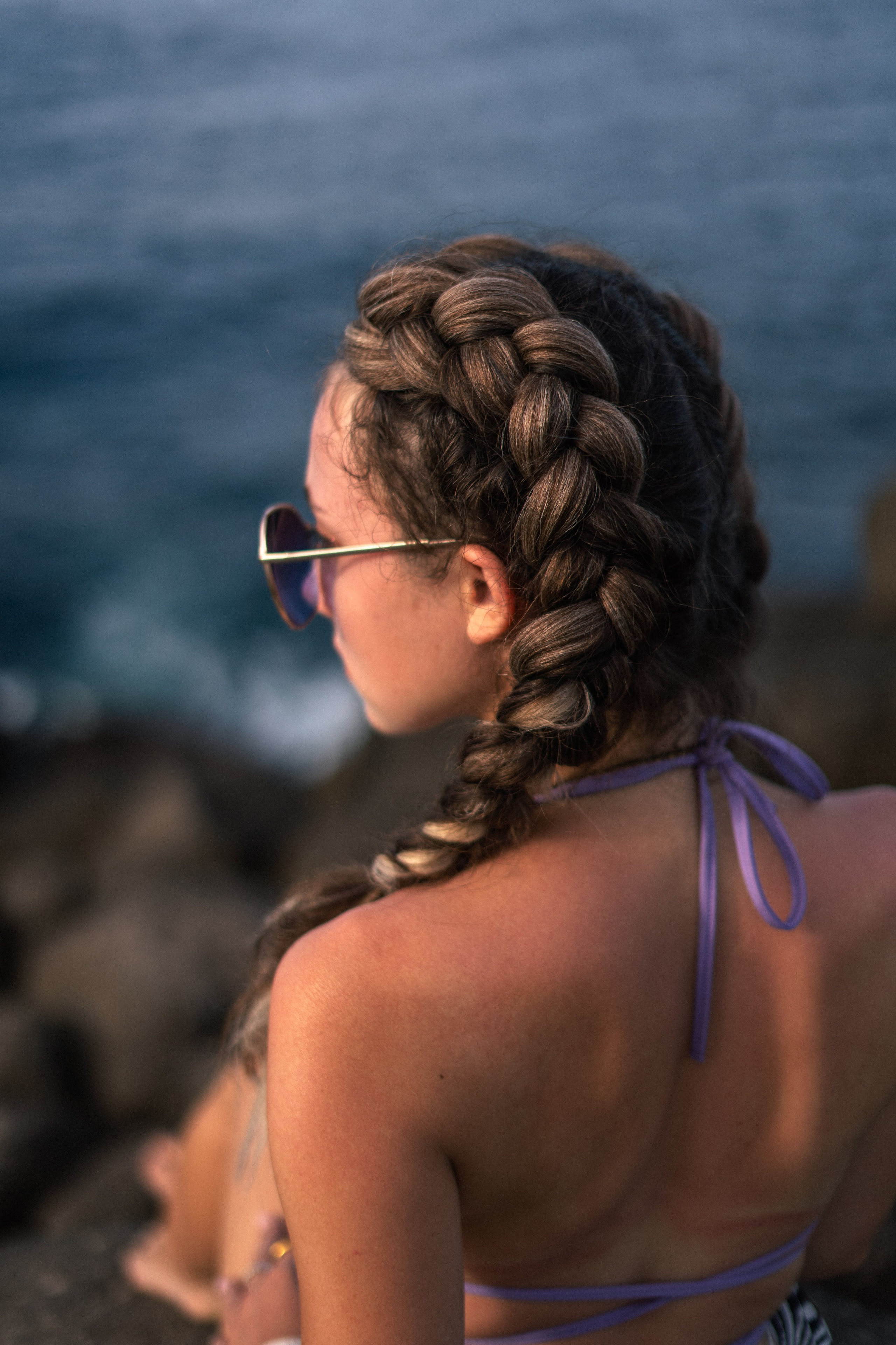 a young girl in a purple swimsuit with flowing hair on the rocks