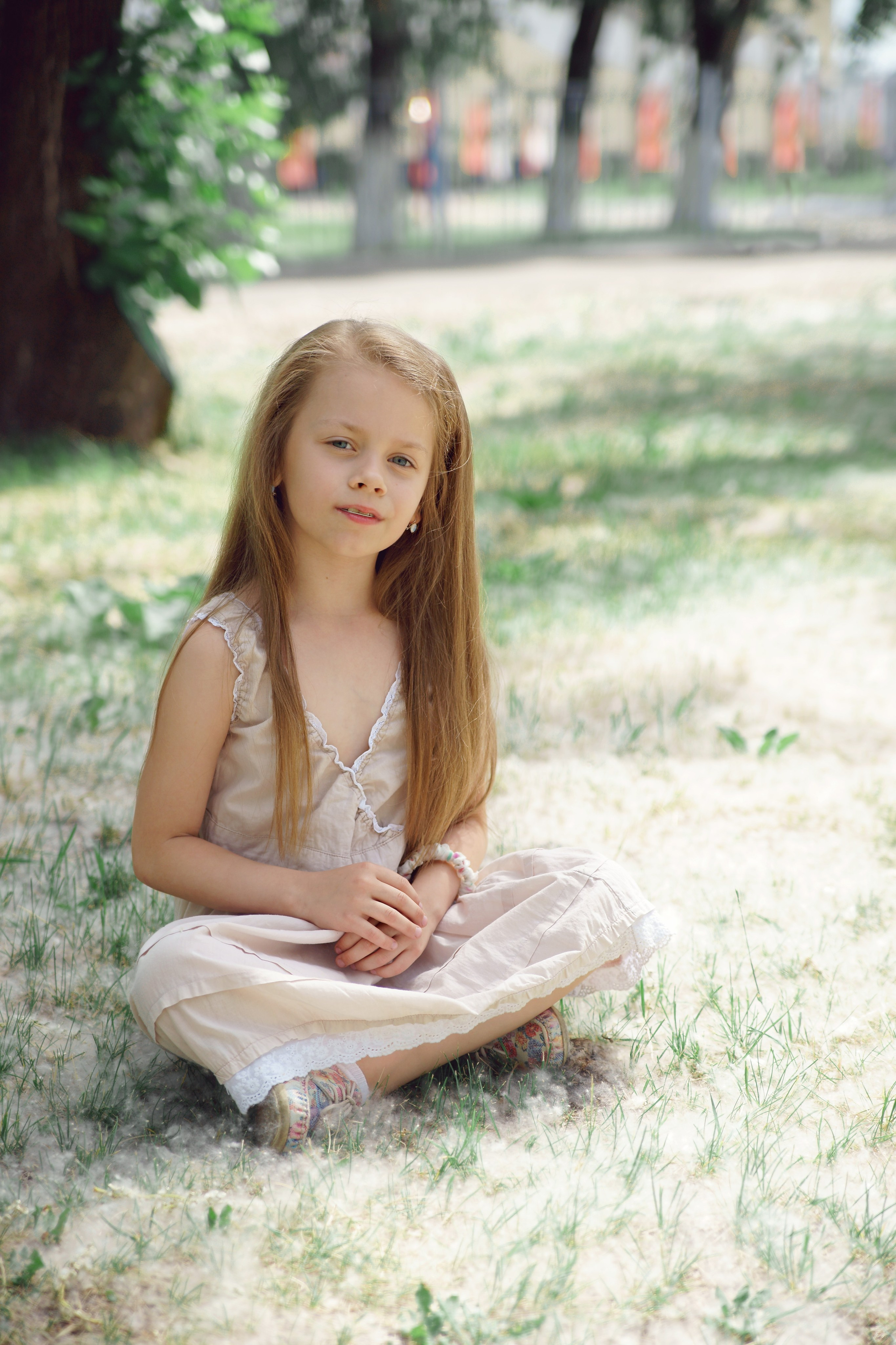 Детская фотосессия летом - девочка сидя на земле с тополиным пухом