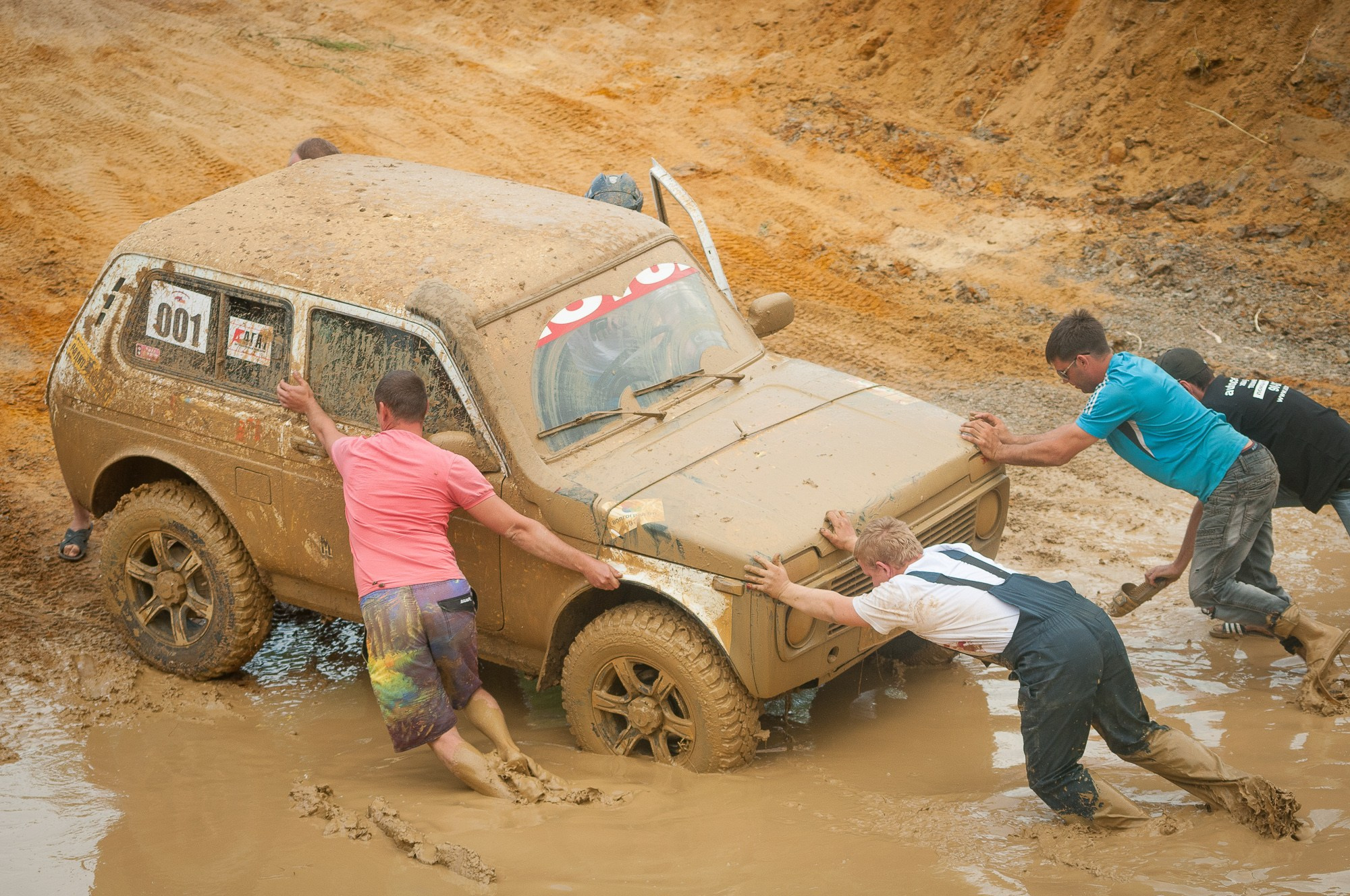 Зрители гонок "Генералы песчаных карьеров" помогают вытолкать застрявший автомобиль из грязи