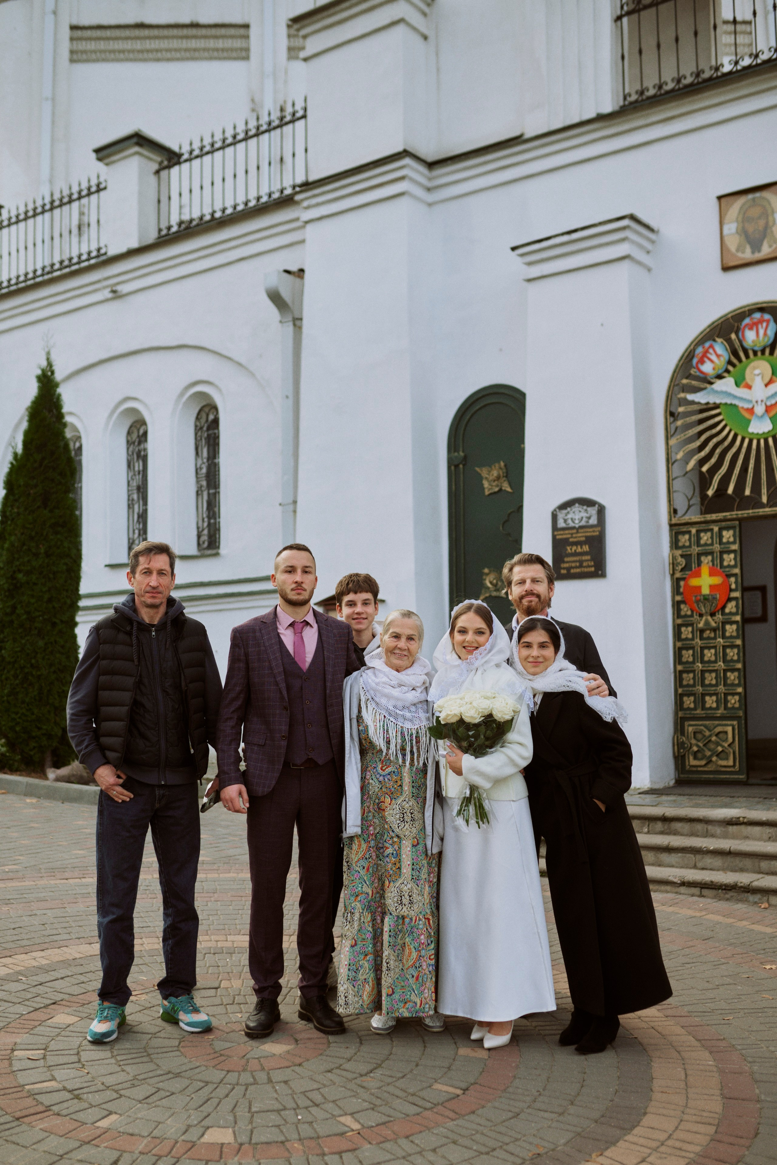 Молодожёны с родителями у храма после венчания — семейное фото