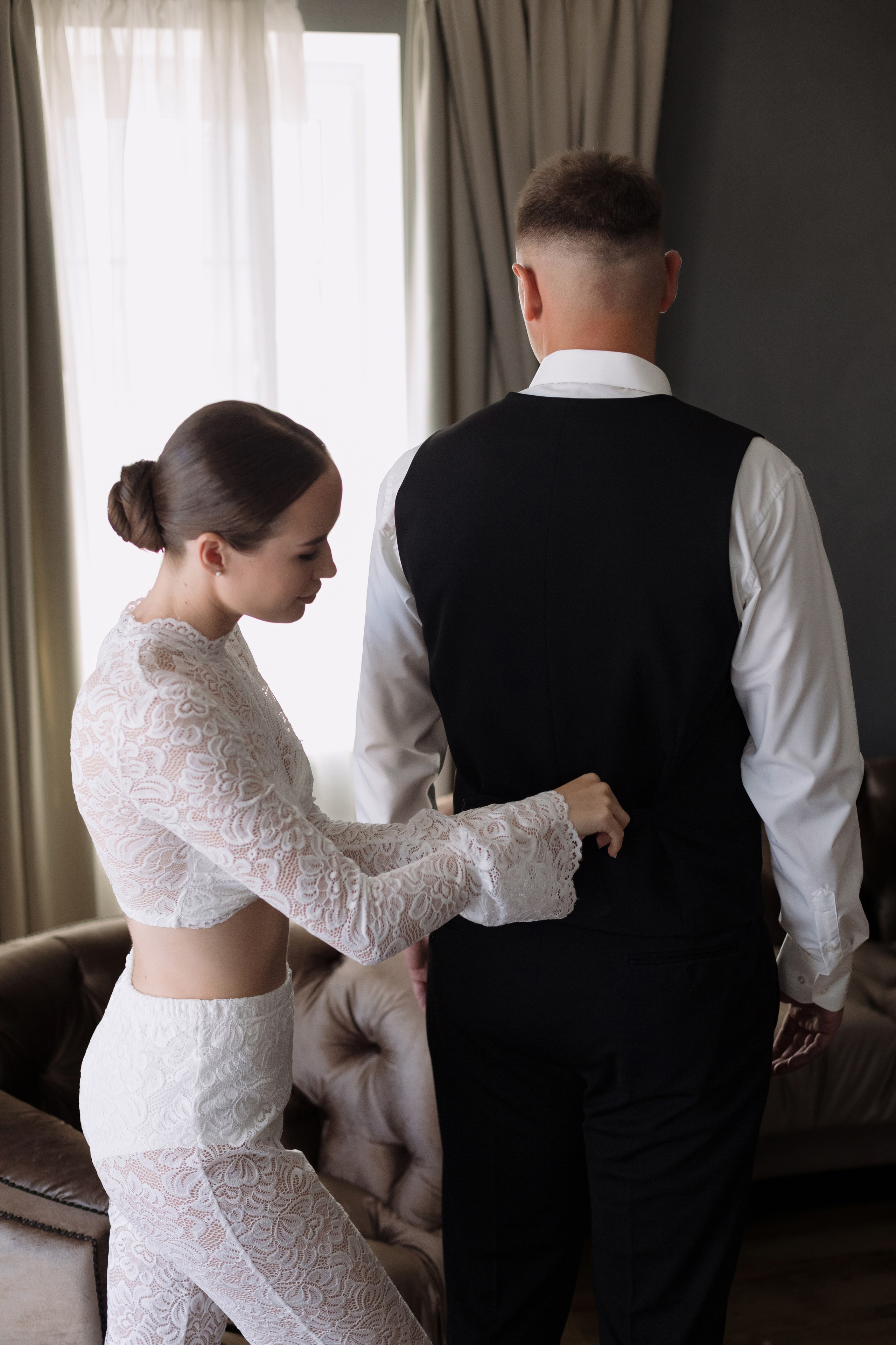 Невеста помогает жениху застегнуть жилет во время свадебных сборов в Golden Horse, Таганрог