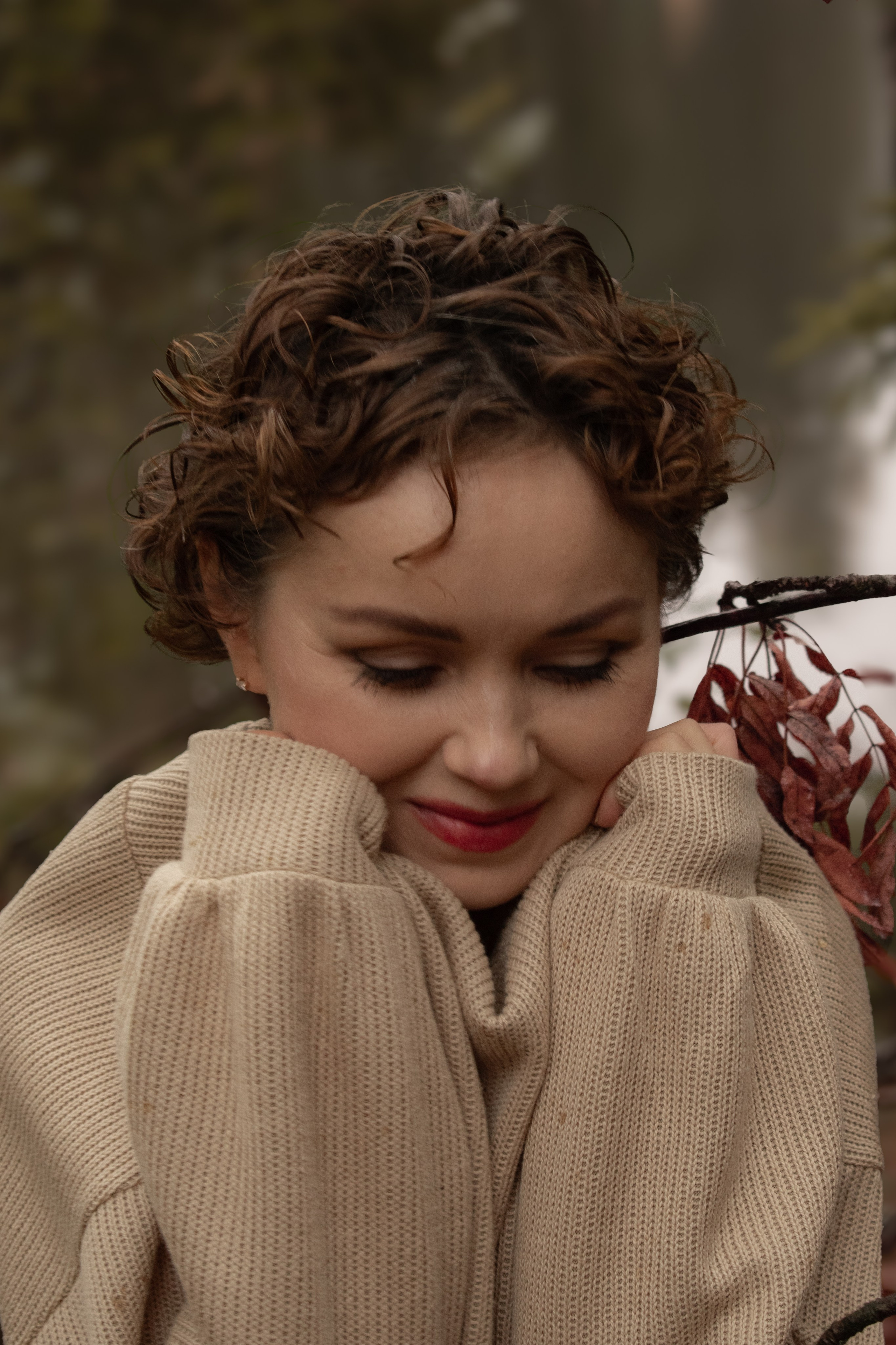 Девушка с короткой стрижкой кутается в свитер