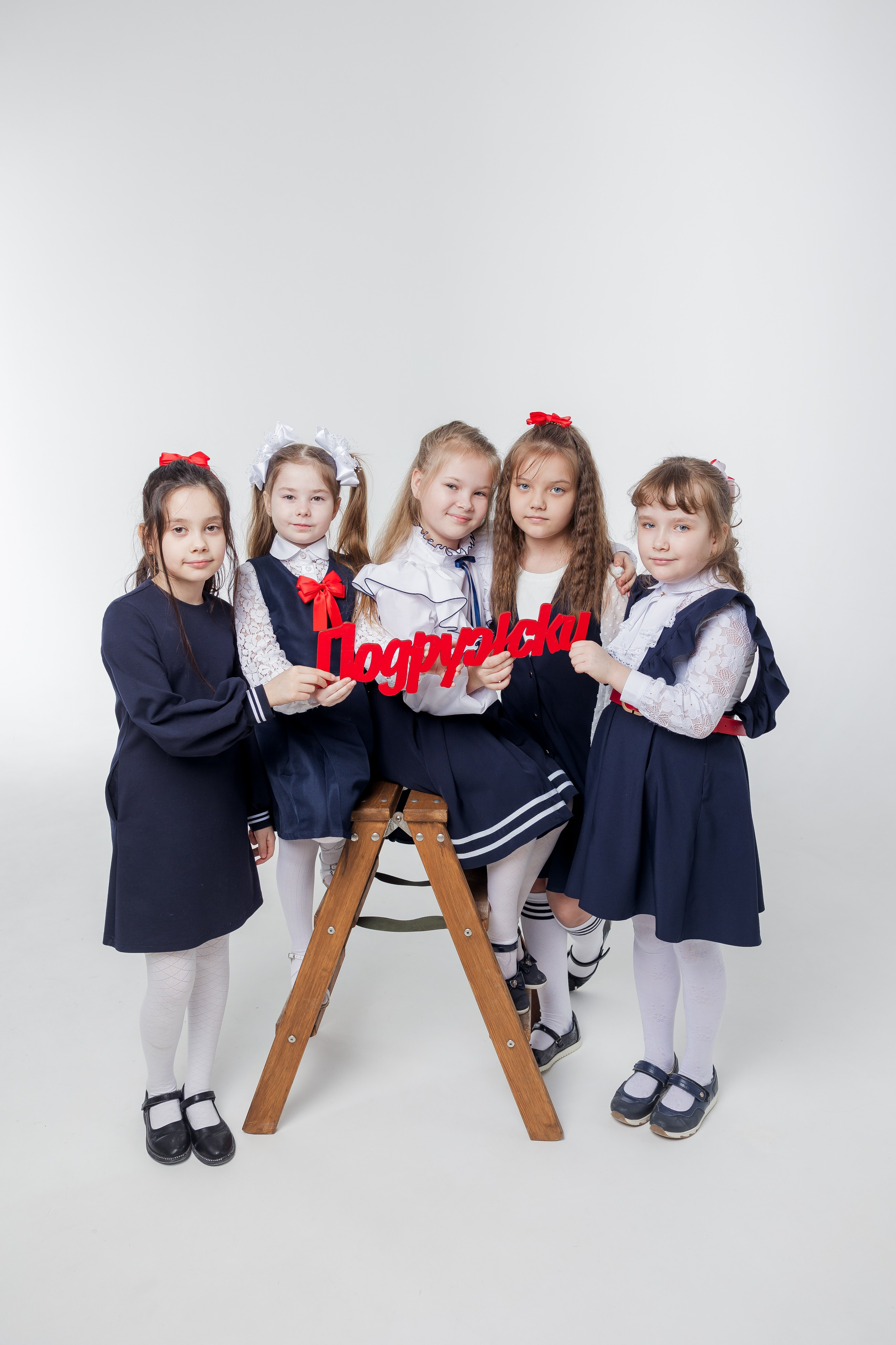 Девочки стоят вместе около лестницы с надписью подружки