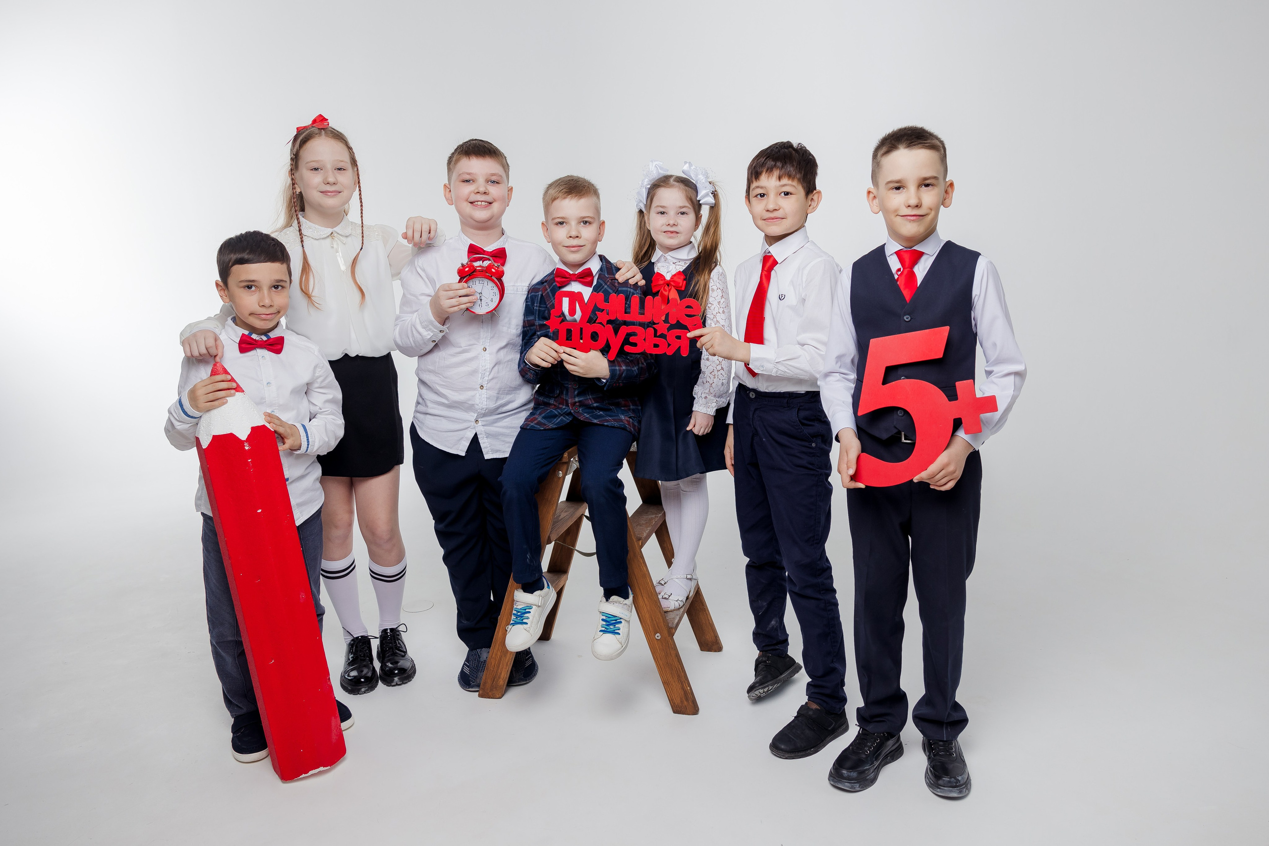 Девочки и мальчики стоят вместе в студии с красным карандашом и надписью лучшие друзья