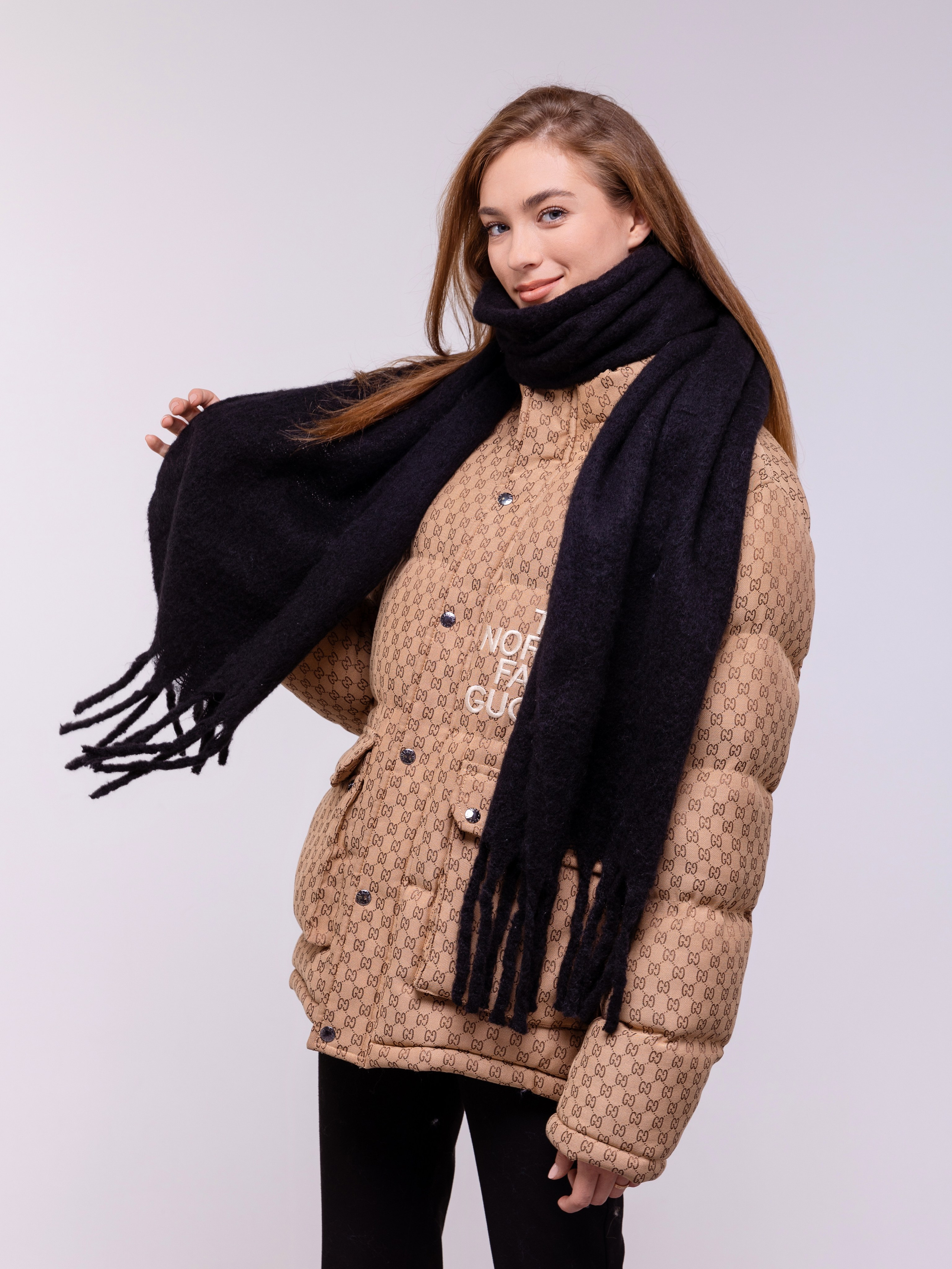 Девушка демонстрирует длинный черный шарф с длинной бахромой.