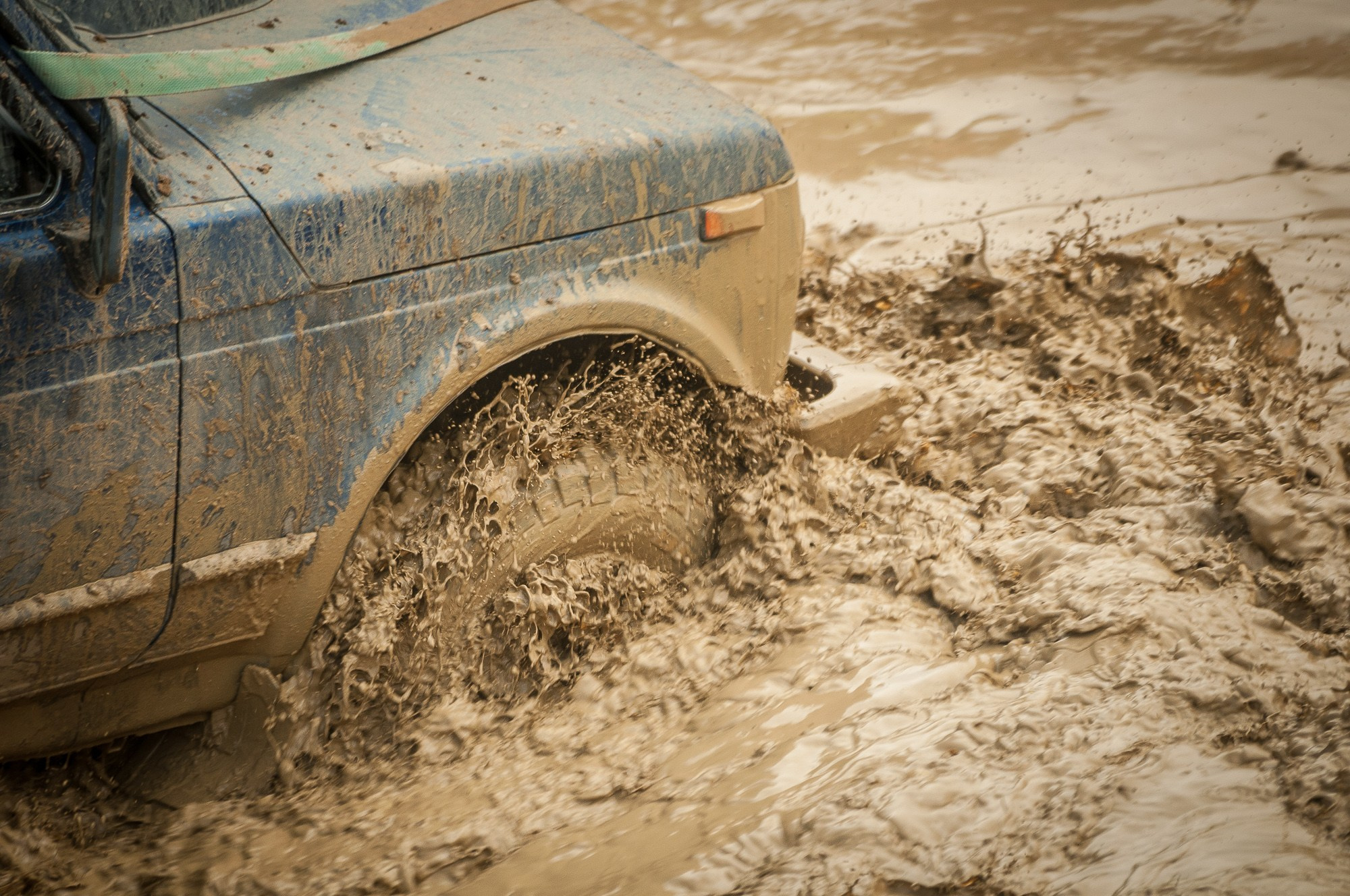 Грязная вода бурлит вокруг колеса автомобиля