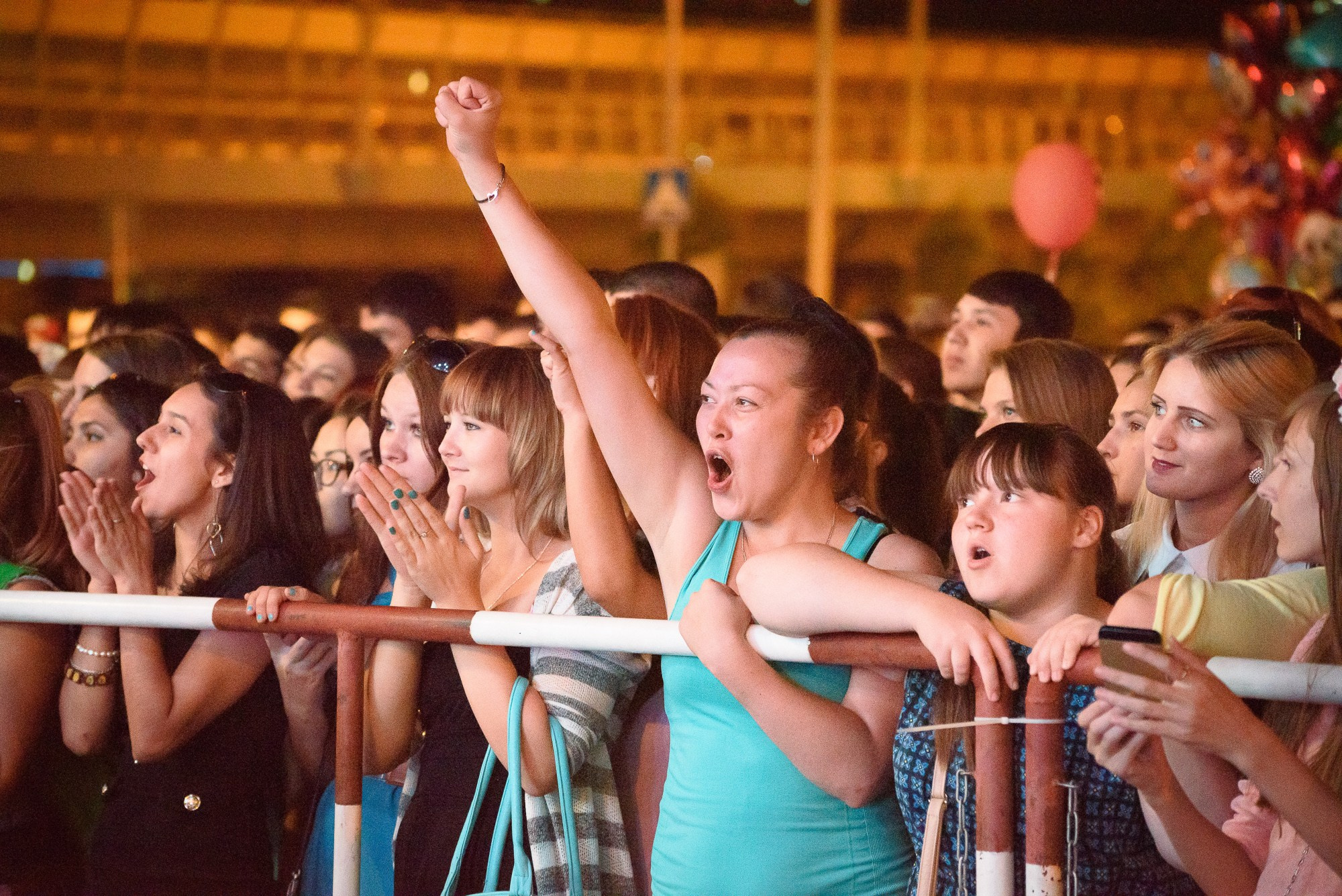 Девушка в толпе зрителей радостно вскинула руку вверх