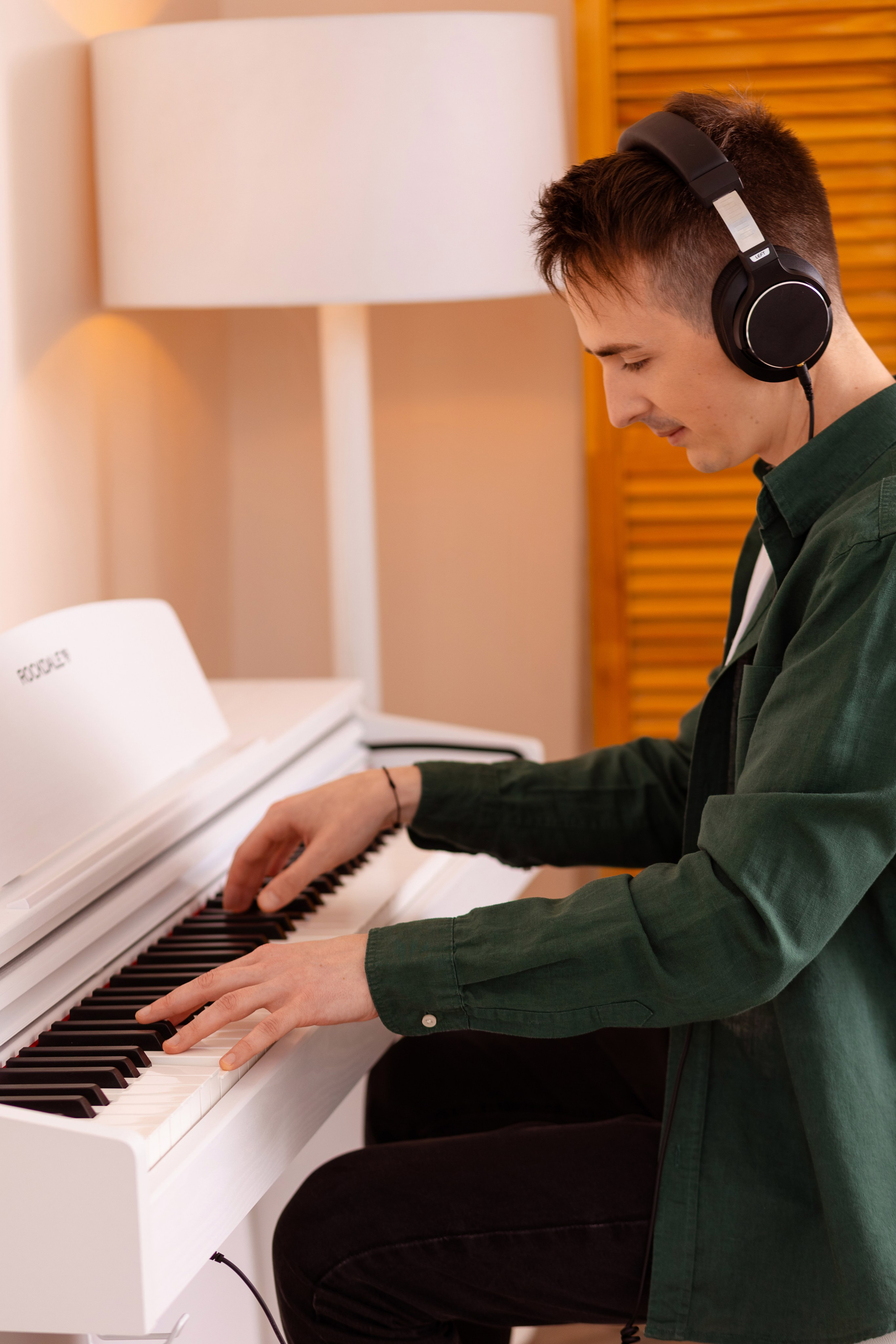 Юноша в наушниках играет на белом пианино.