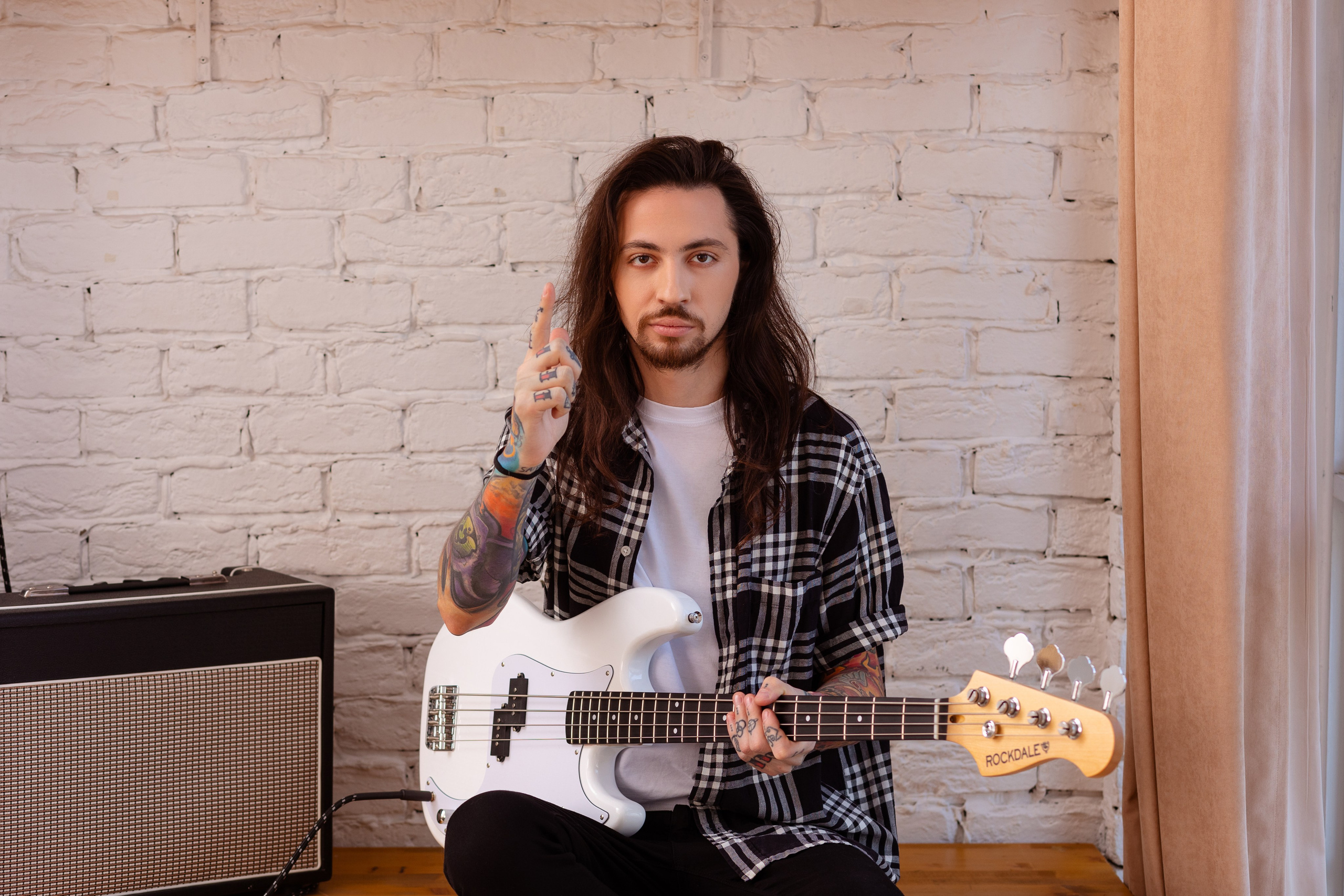 Музыкант на портрете держит в руках белую электрогитару.