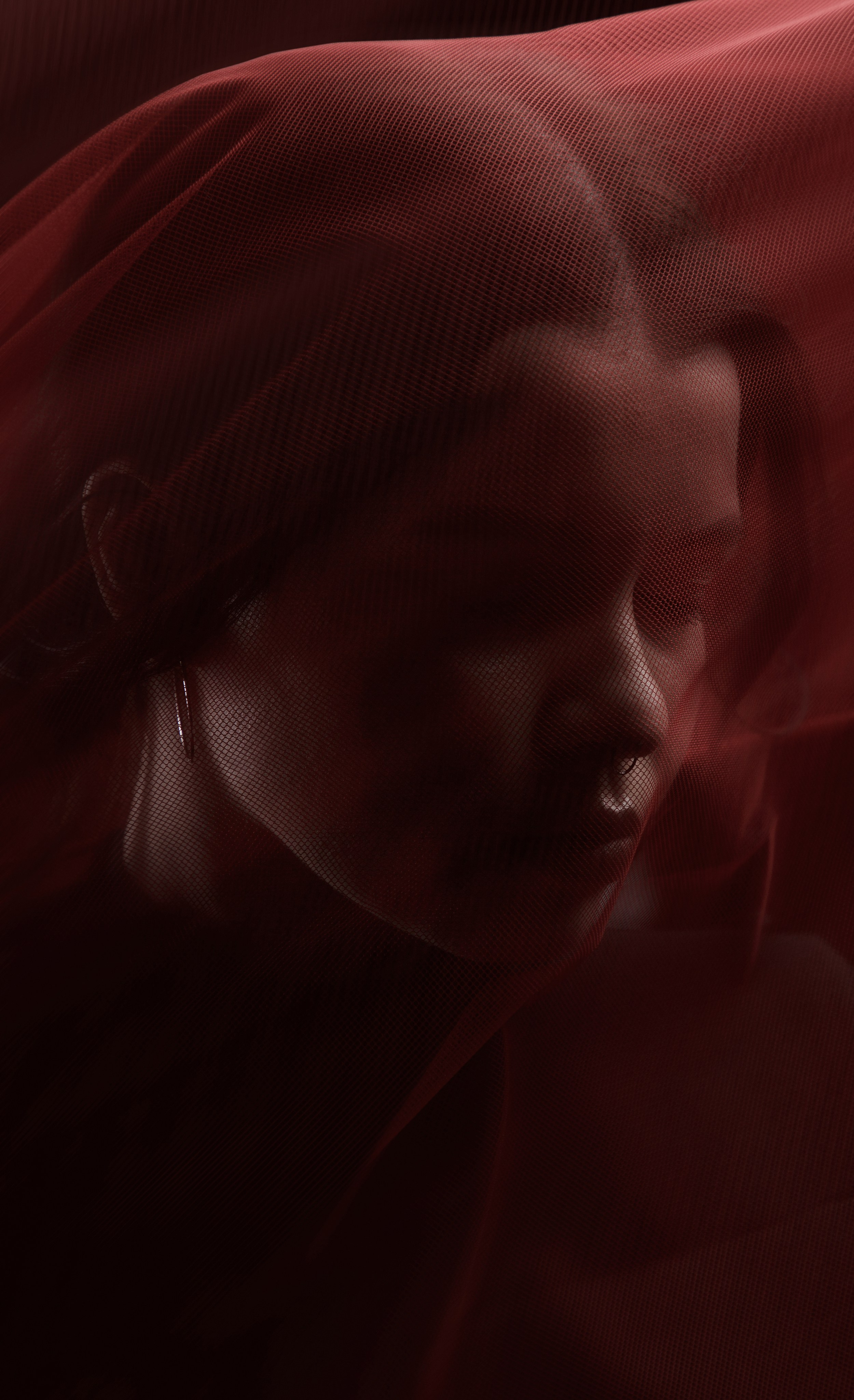 Драматичный студийный женский портрет с летящей красной тканью. 