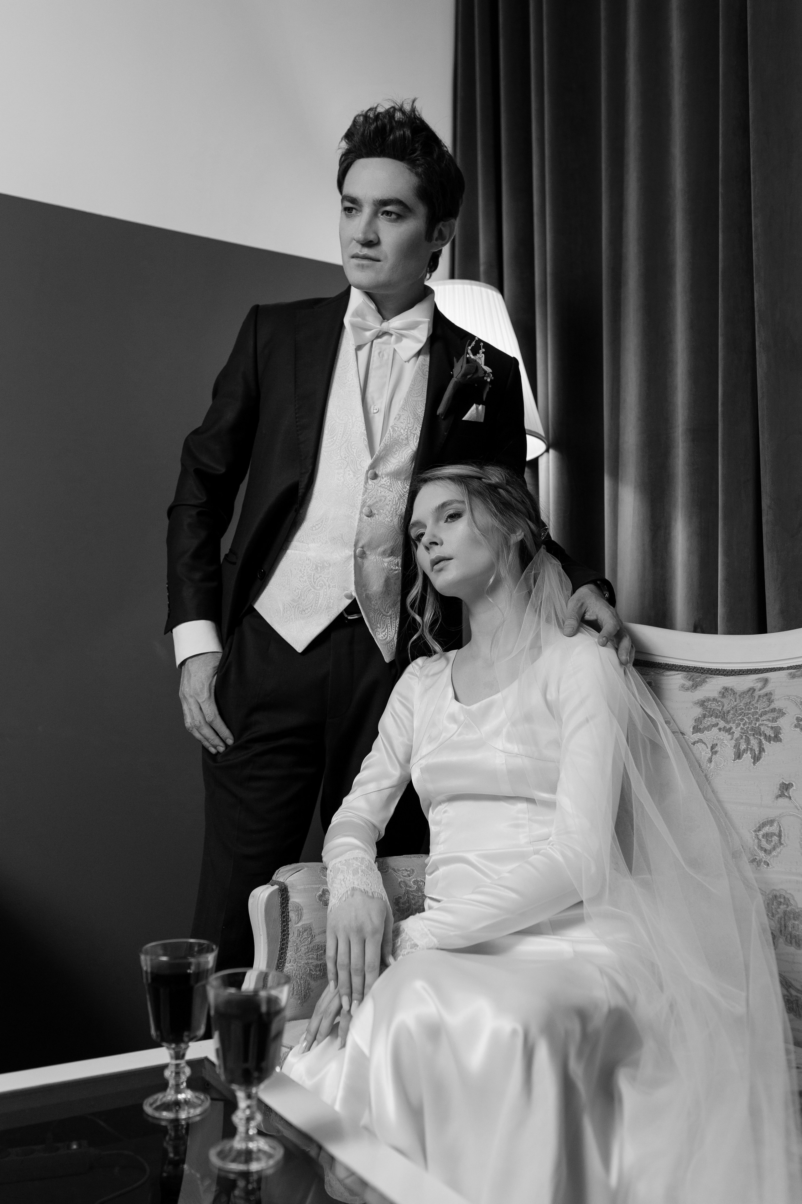 Невеста сидит на диване, сзади стоит жених, положив руку на плечо невесты.