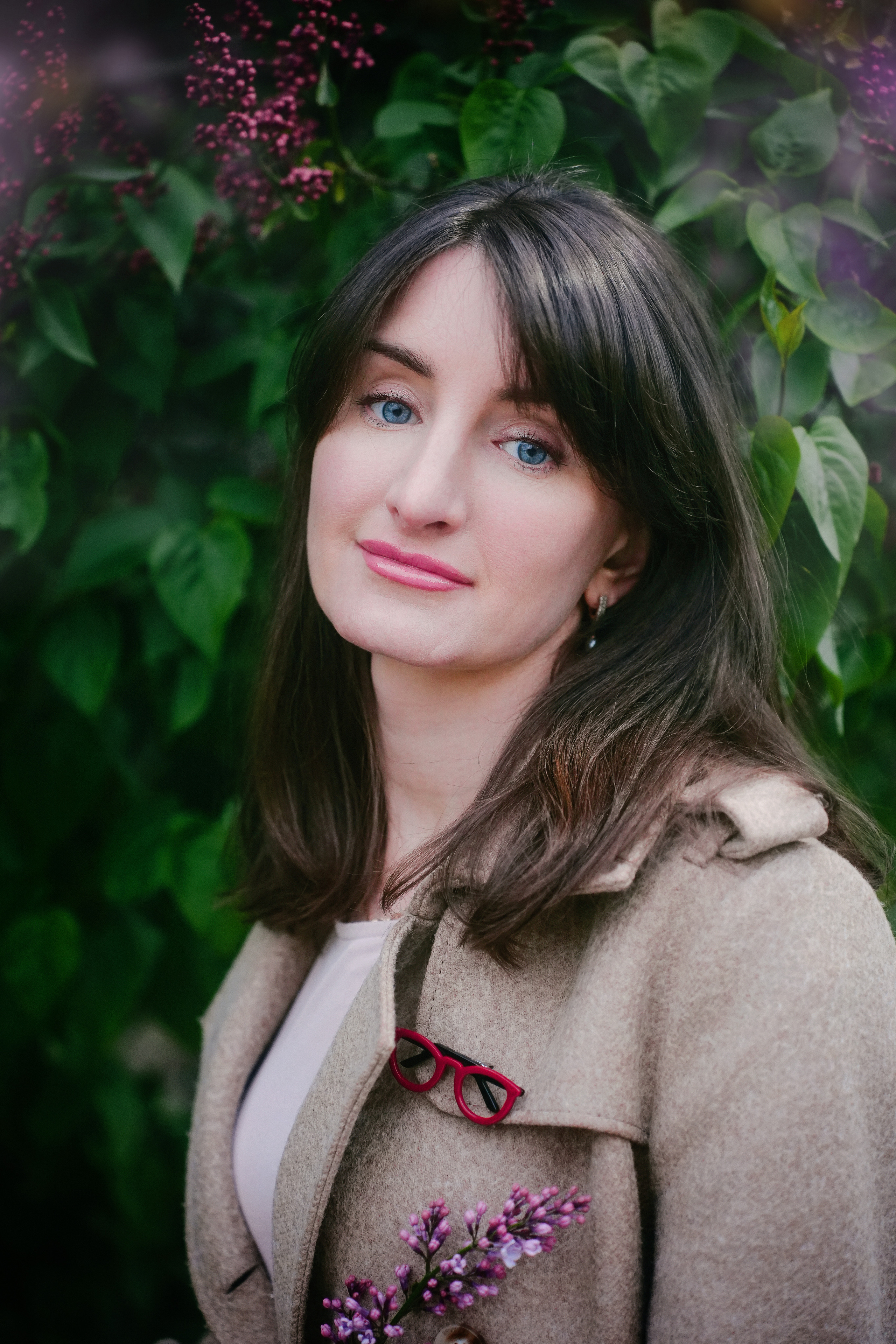 В сирени прекрасный крупный портрет молодой женщины брюнетки в коричневом тренче