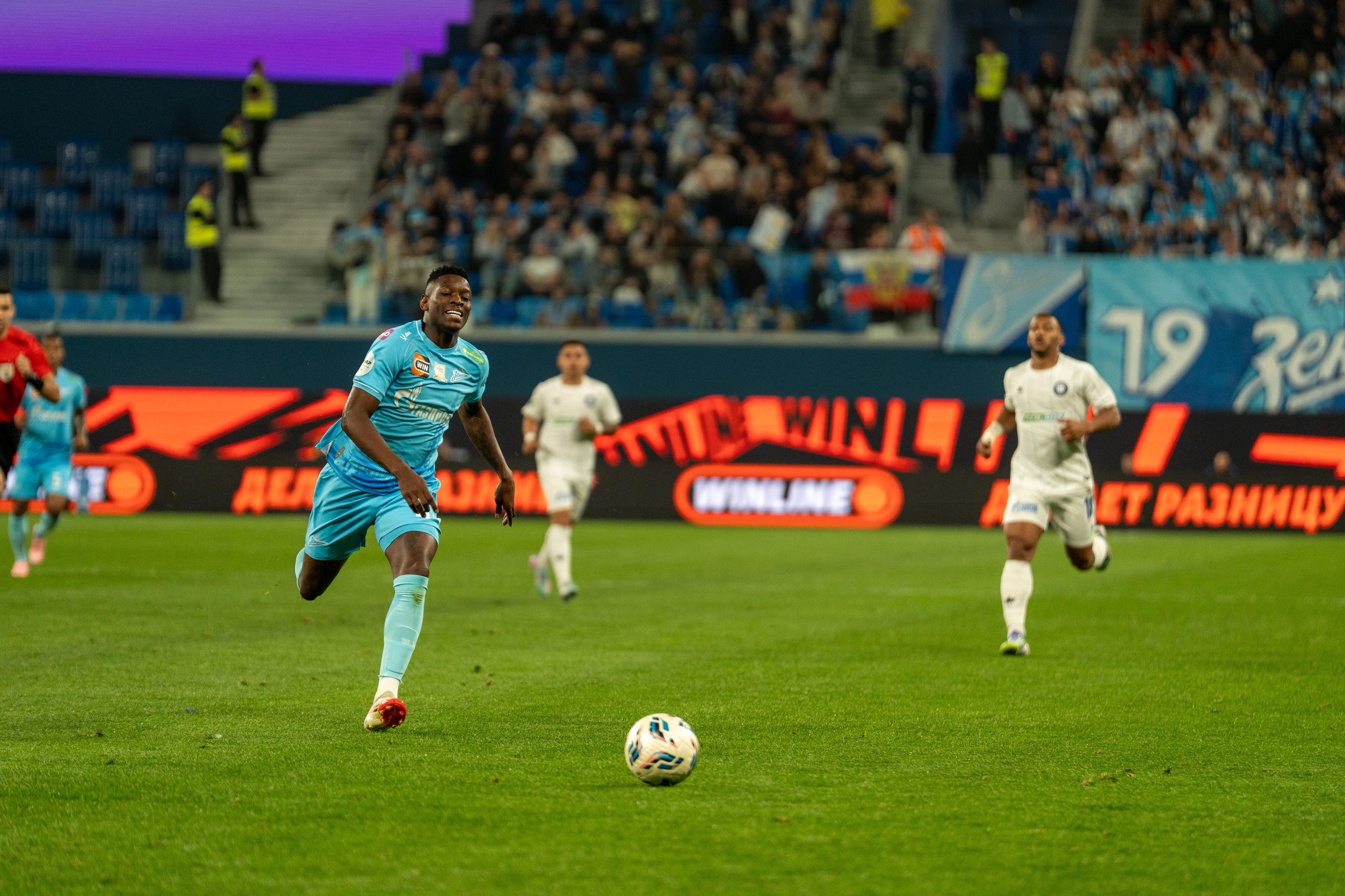 Игрок Зенита в голубой форме гонится за мячом на Газпром Арене — спортивный фотограф Санкт-Петербург