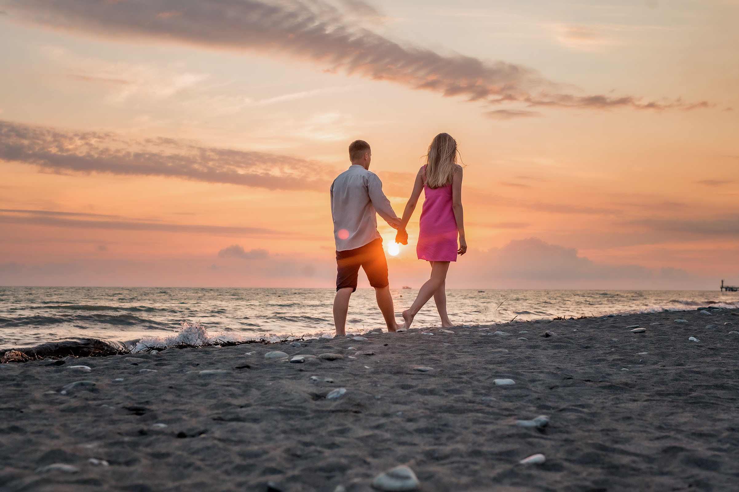 Гуляющая пара на закате летом в Сочи у моря.