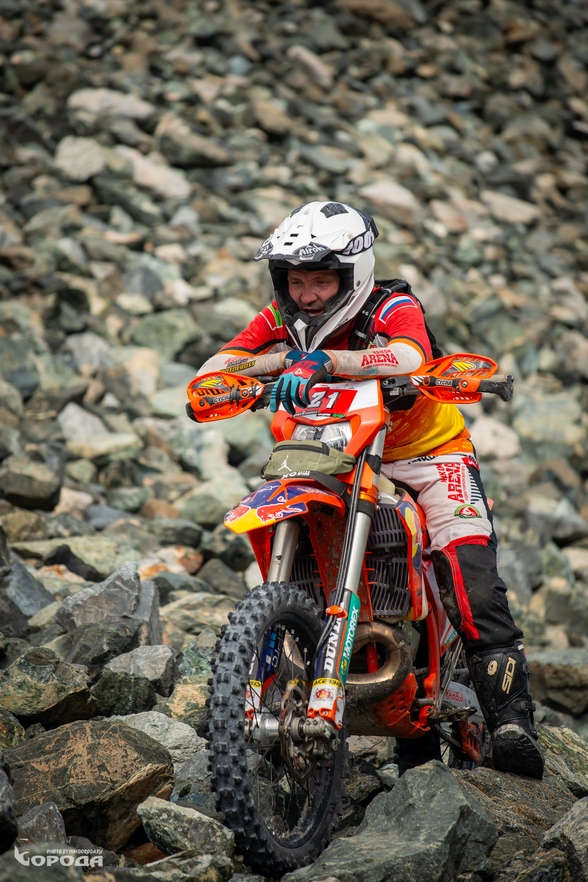 Эндуро-спортсмен в красно-белой экипировке покоряет сложный рельеф