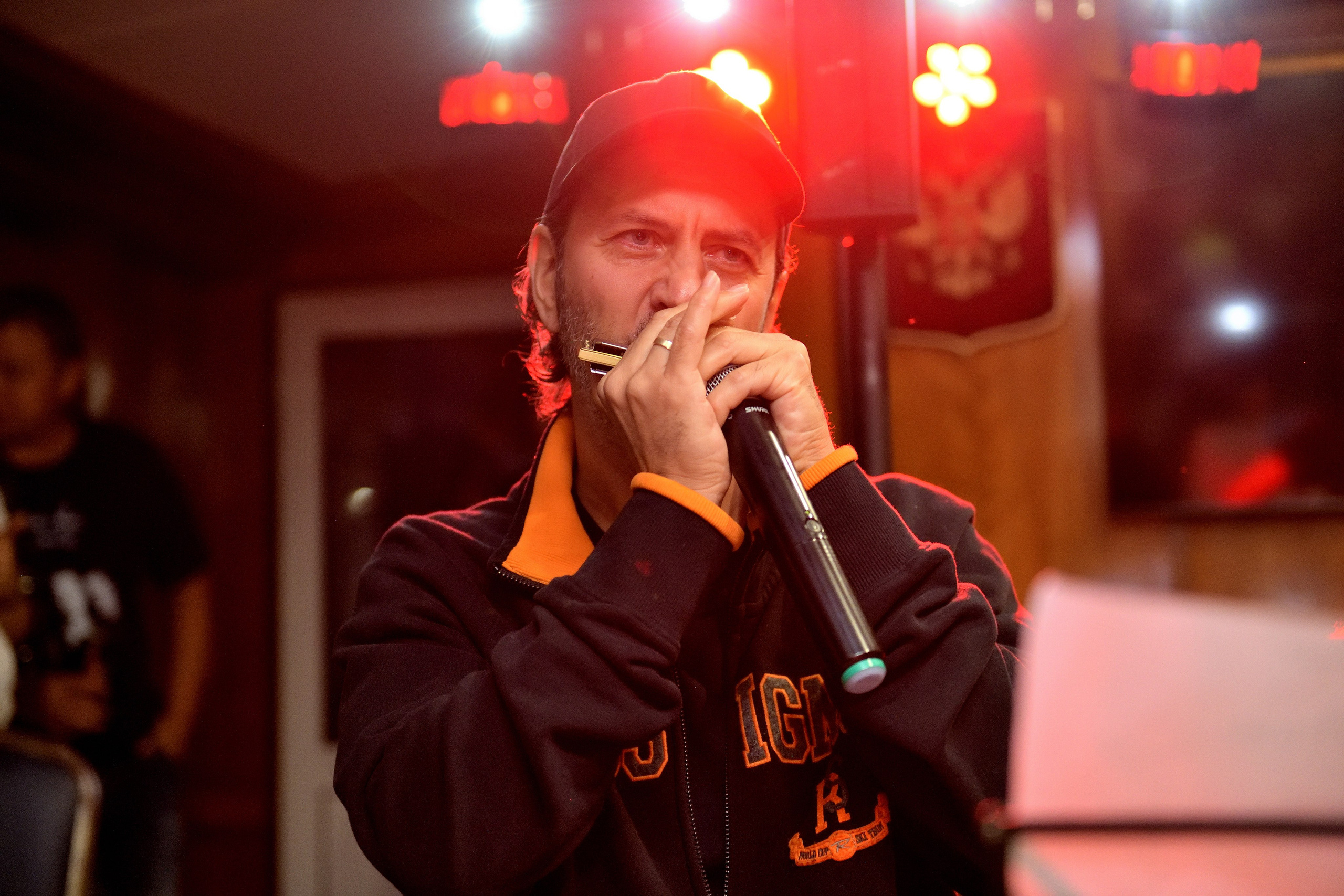 "Музыкант играет на губной гармошке во время выступления группы DM Acoustics".