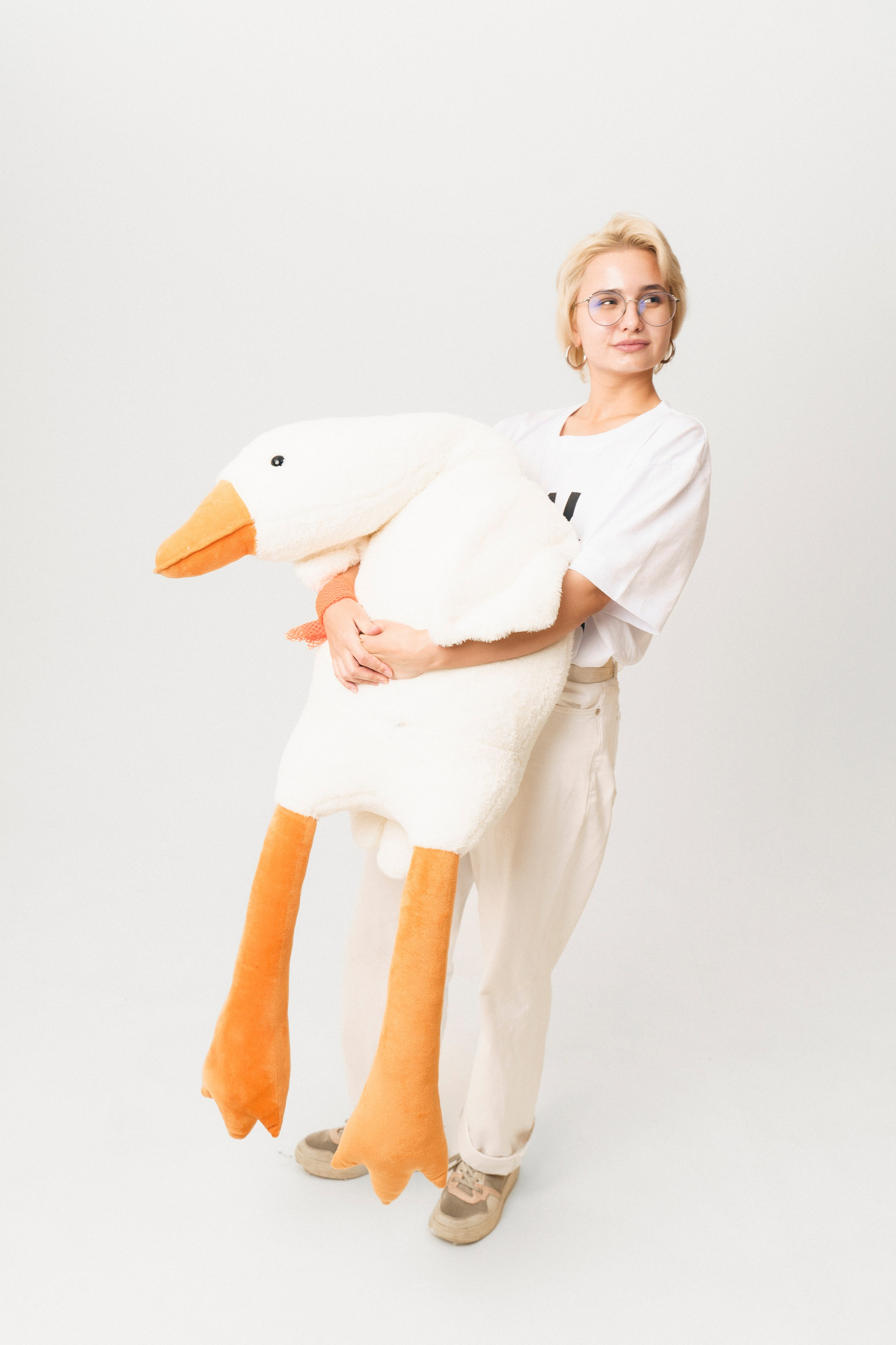 Девушка держит большого плюшевого гуся в руках