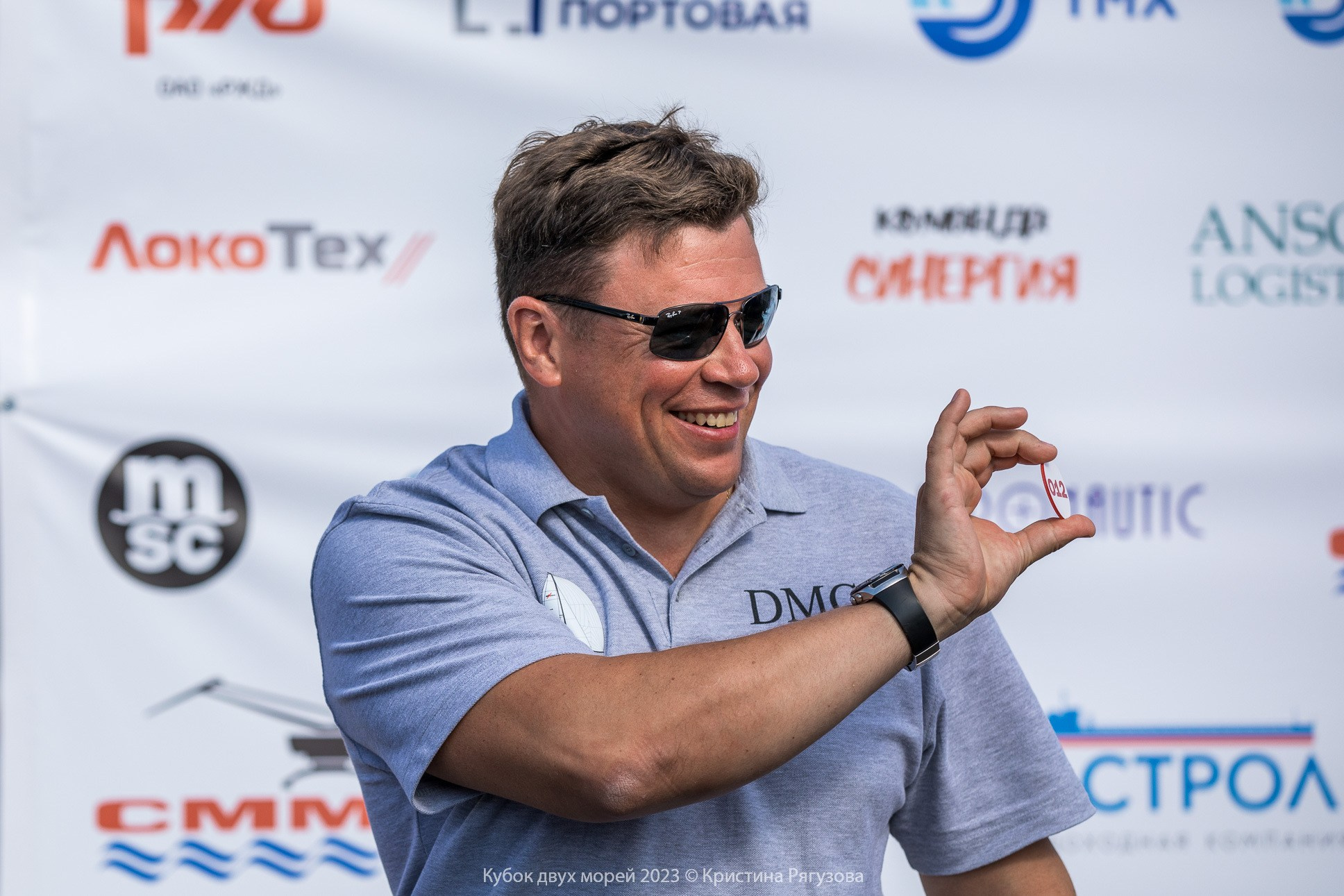 Участник большой парусной регаты Кубок двух морей на жеребьевке перед гонками. Портрет мужчины в очках с улыбкой.