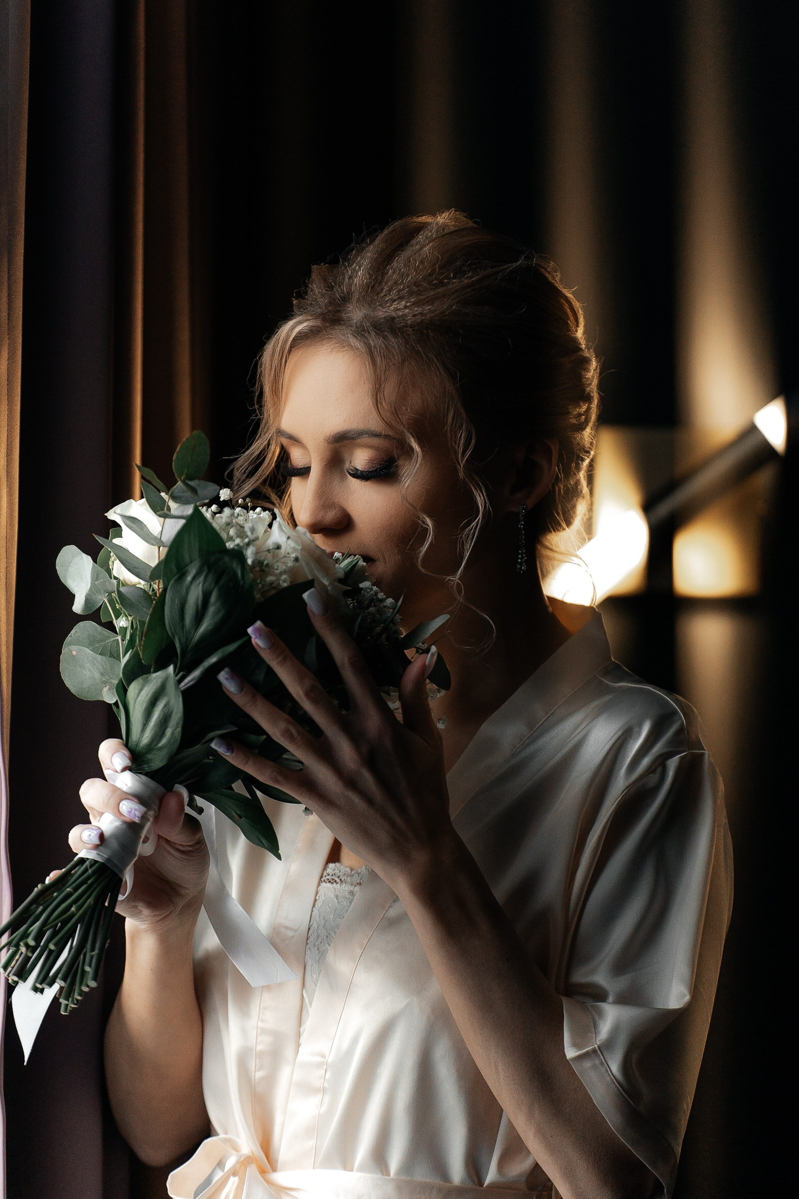 Сборы невесты в отеле Аквалина. Невеста стоит у окна и нюхает букет невесты