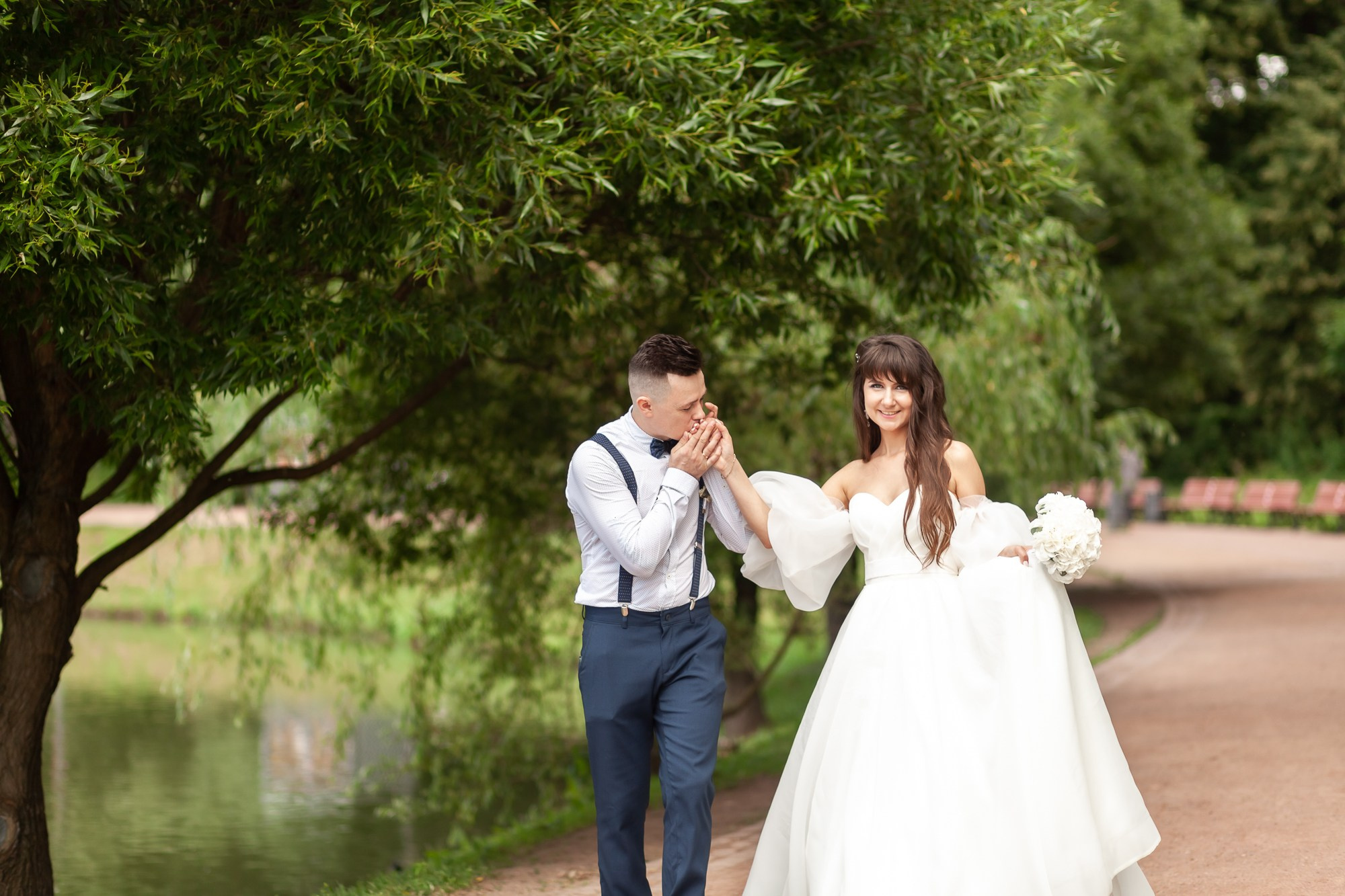 Жених целует руку невесте на фоне зелени