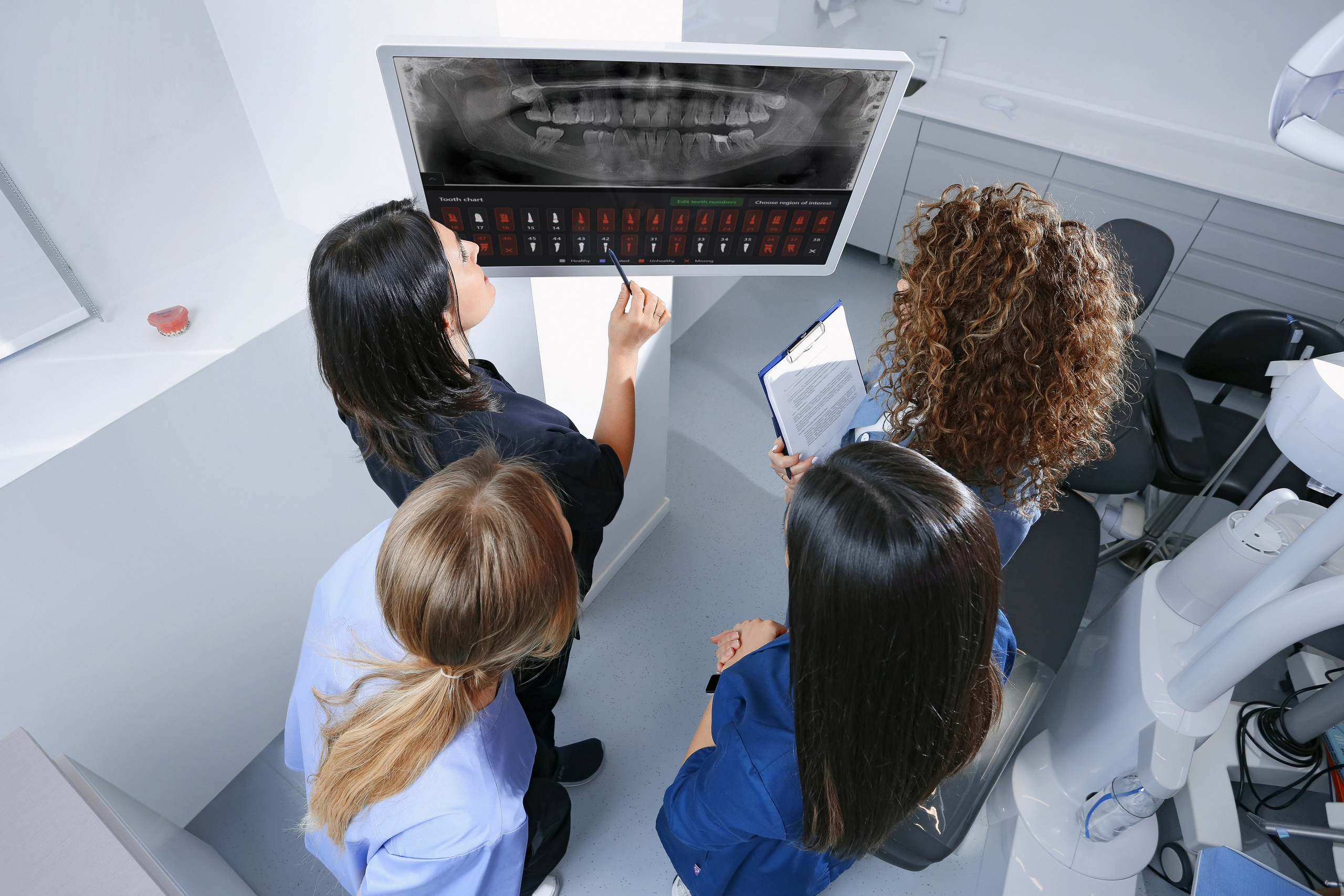 Консилиум врачей стоматологов с помощью искусственного интеллекта Diagnocat составляют план лечения, изучая панорамный снимок