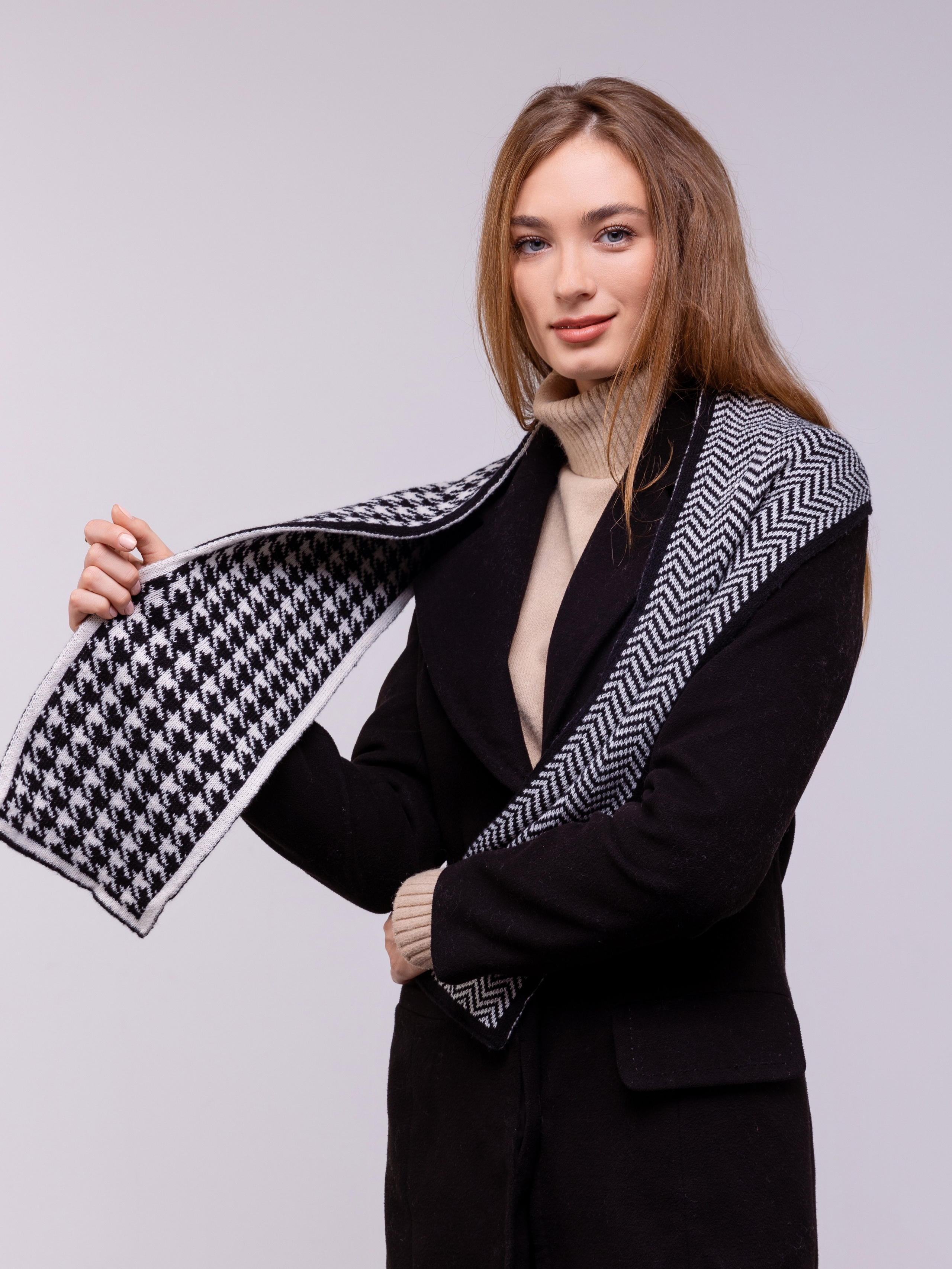 Девушка показывает половину шарфа с крупным рисунком.