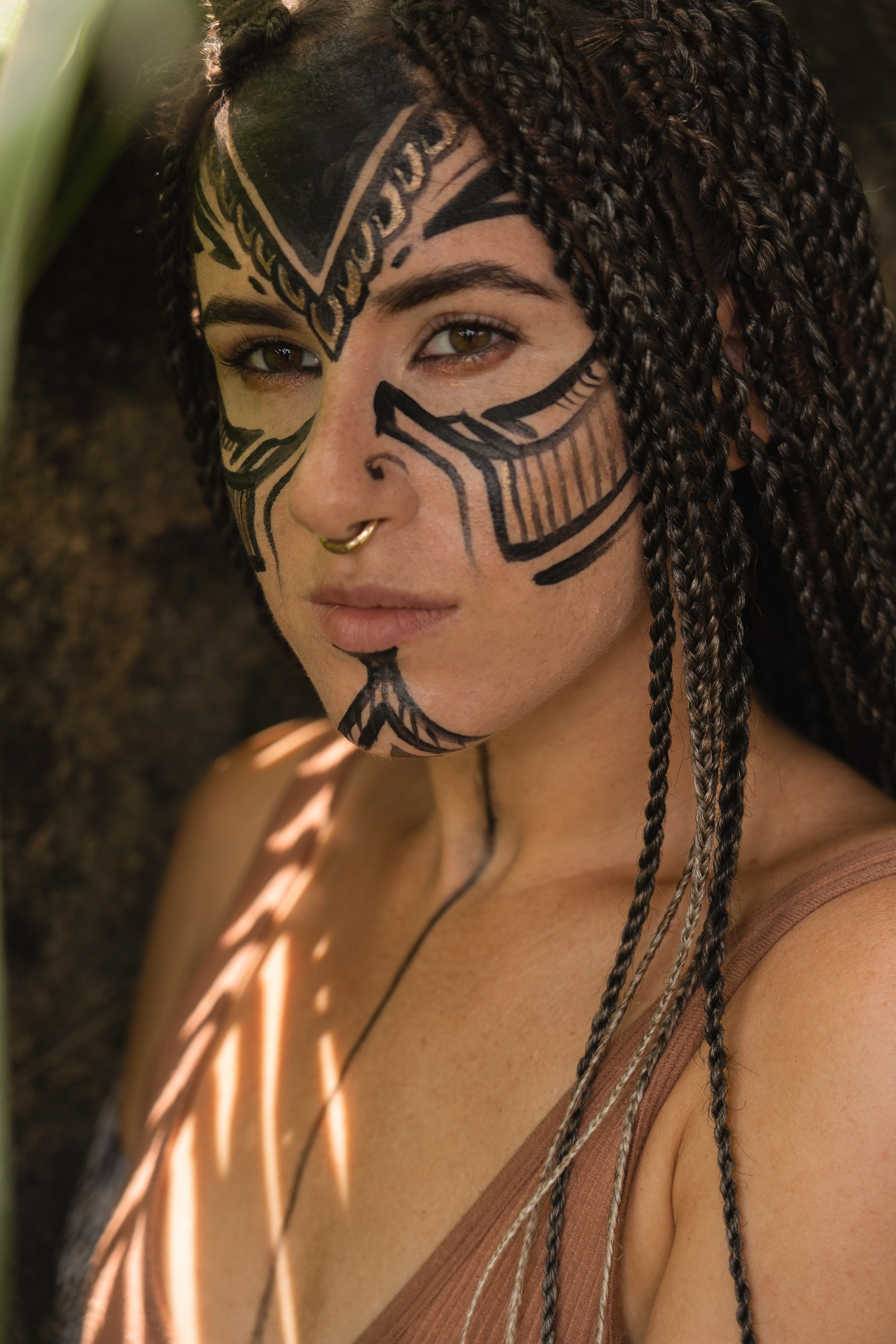 a girl with braids and face paint among tropical trees and plants