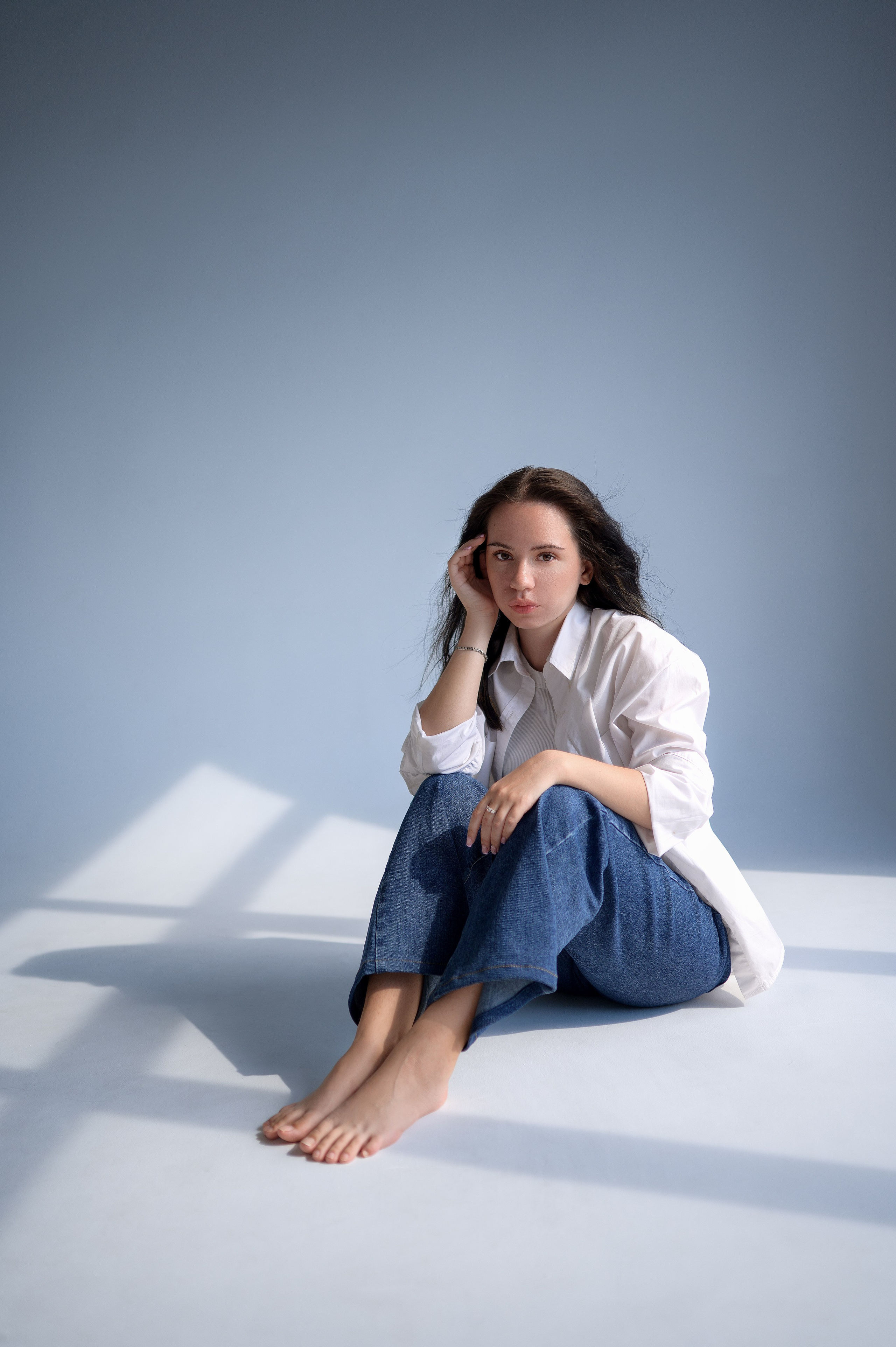 Минималистичный портрет в студии: девушка в повседневной одежде на белой циклораме. Игра света и теней от оконных лучей. Волгодонск, студия «Rassvet»