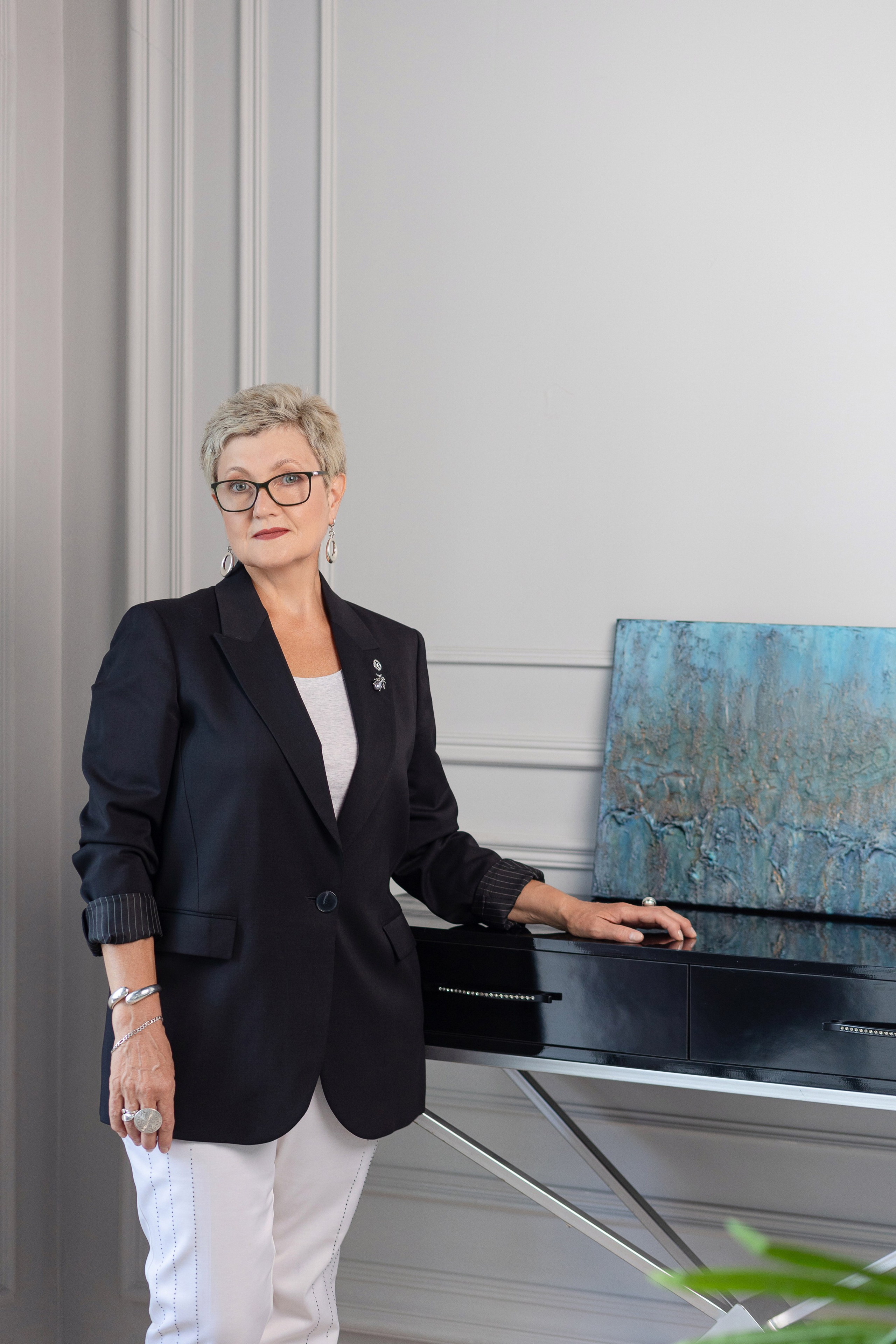 Женщина стоит у стола, на котором находится картина в голубых тонах.