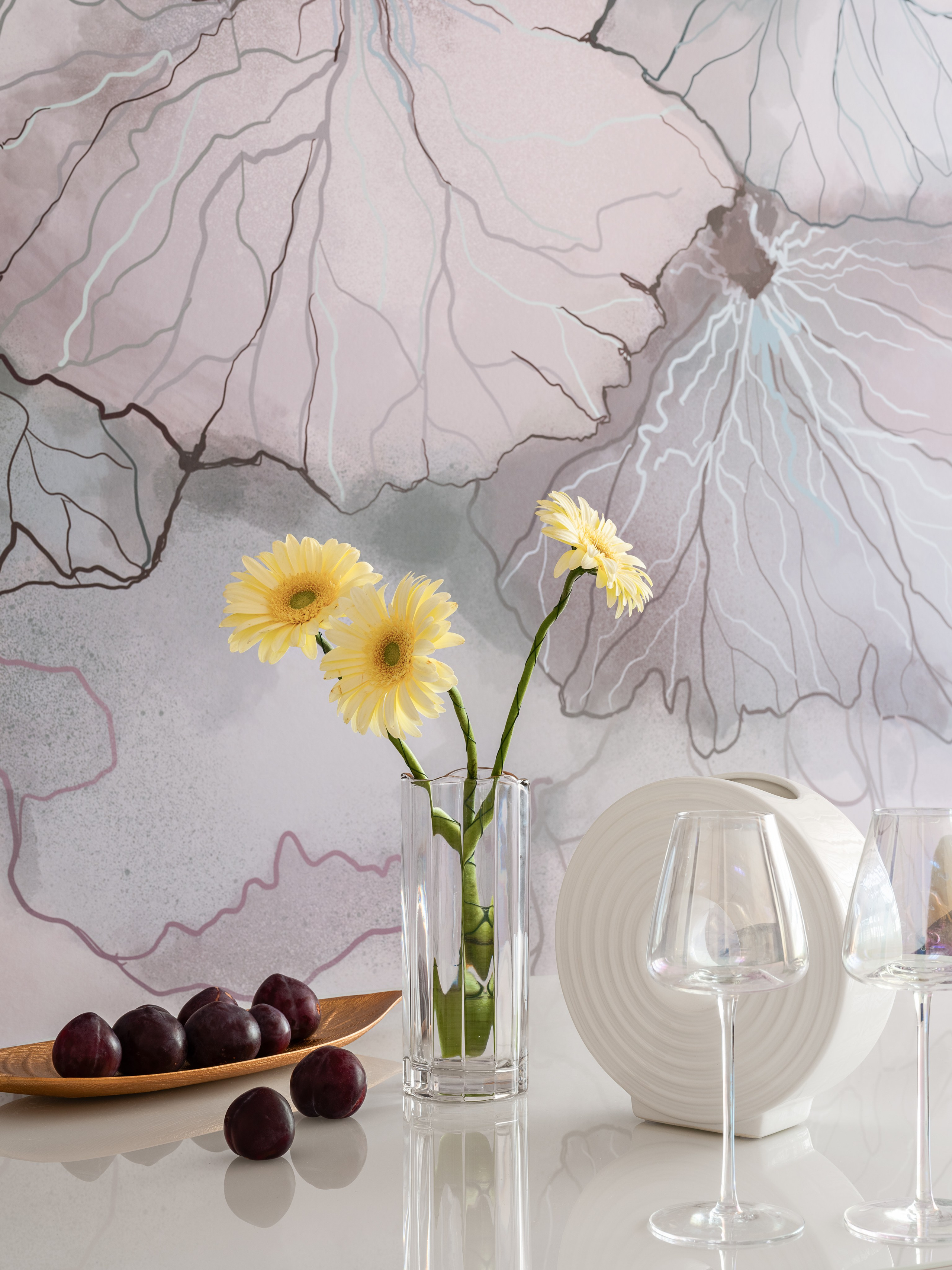 Декор столовой зоны: прозрачная ваза с желтыми герберами, дизайнерская керамика и фрукты на белом столе на фоне художественной стены; гармоничный натюрморт в интерьере от дизайнера Натальи Бунеевой, стилиста Натальи Якушевой, фотографа Сергея Денисенко.