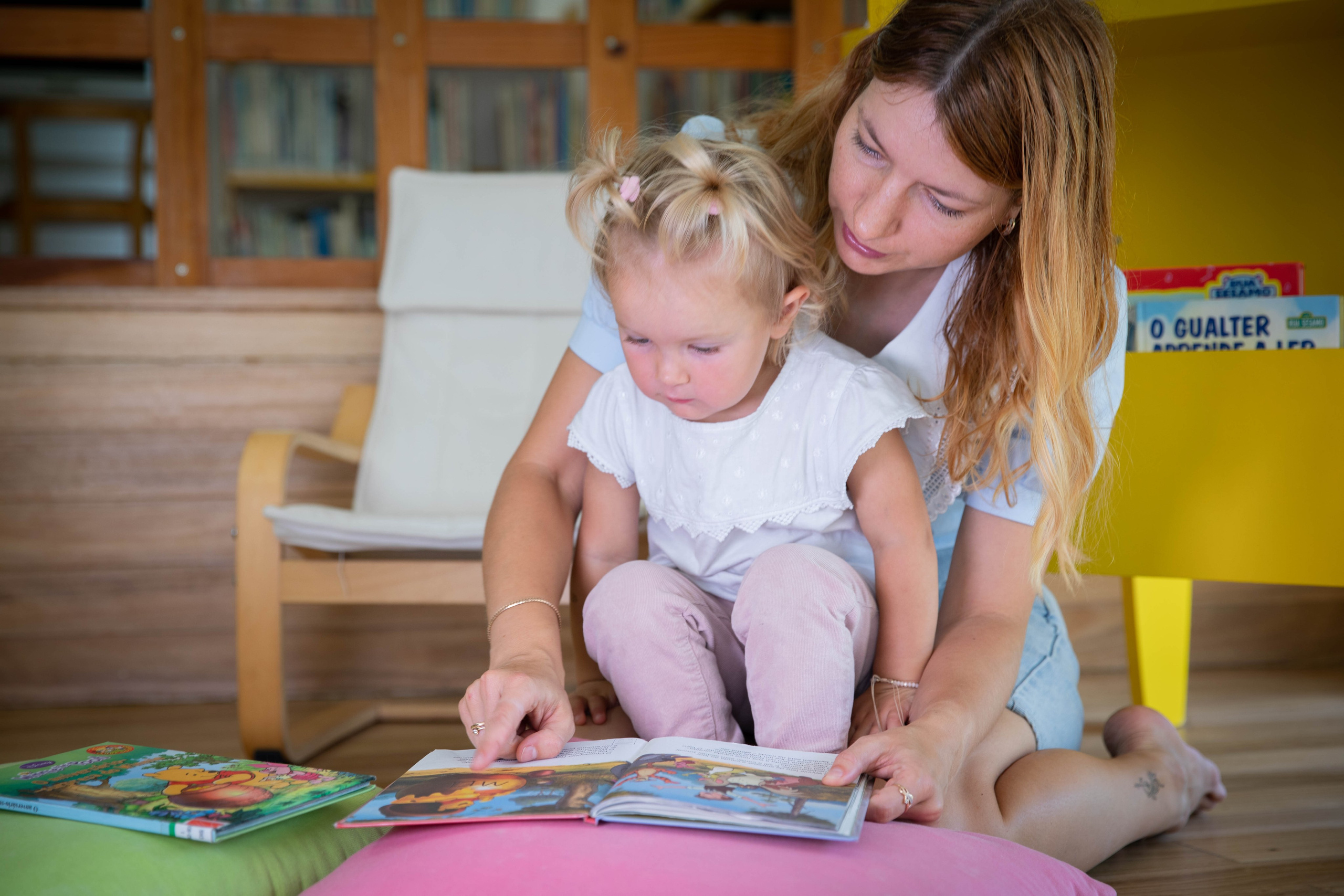 A little girl with a big smile, lost in the pages of an exciting book.
