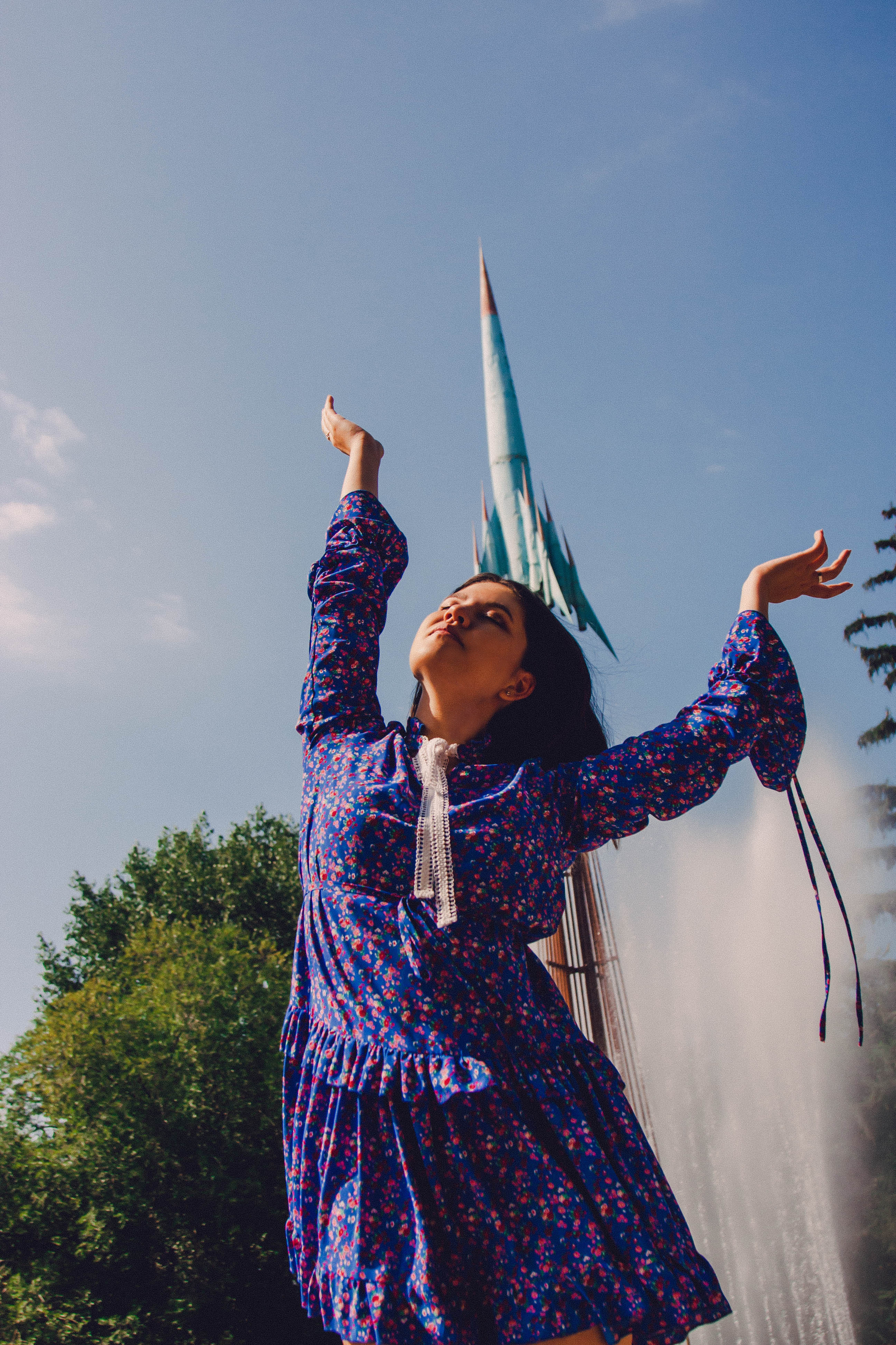 Классный портрет девушки. Женщина в синем платье крупно, на фоне самолет и фонтан, струя воды на фоне.