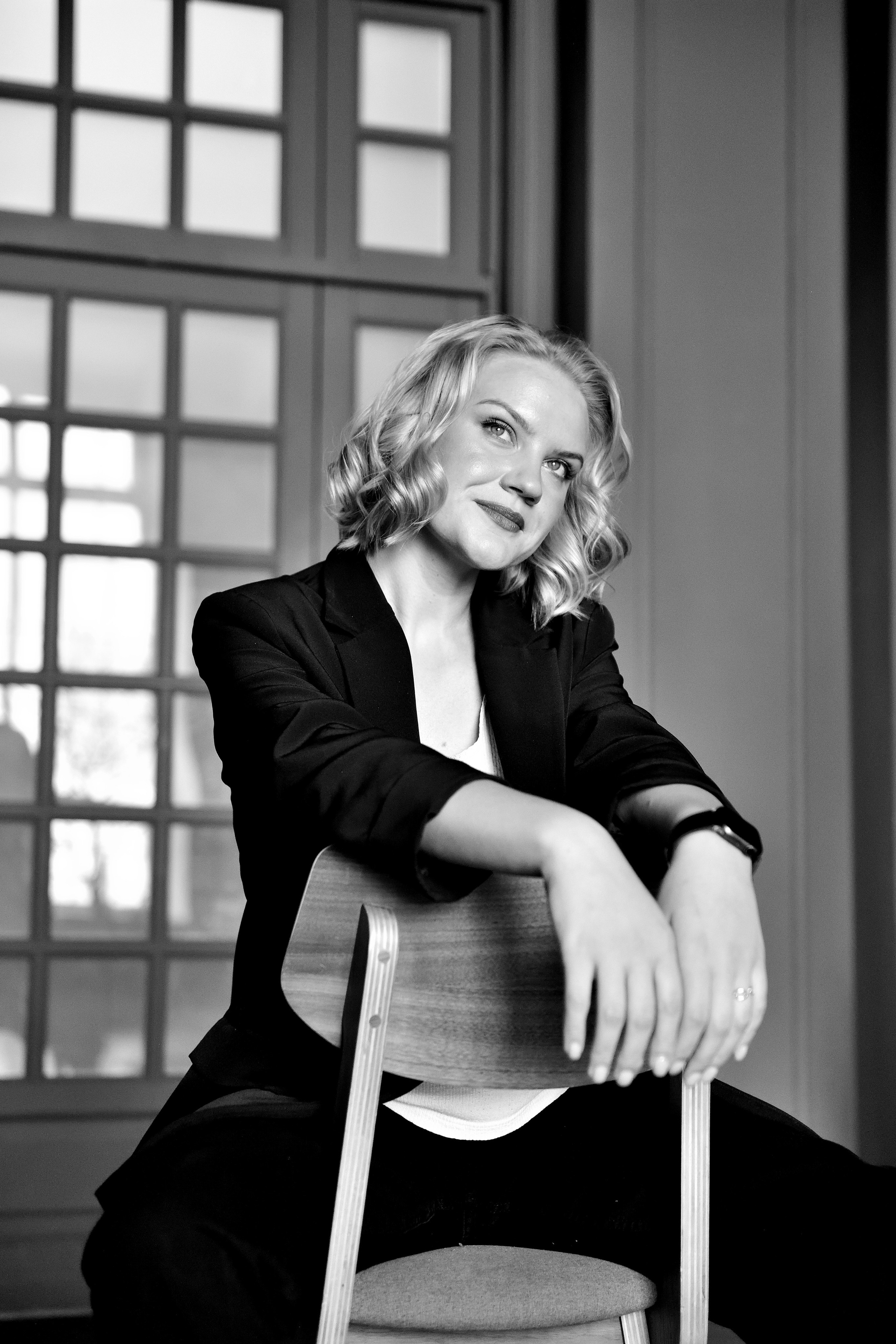 Черно-белая фотография девушки на фоне стула в фотостудии.