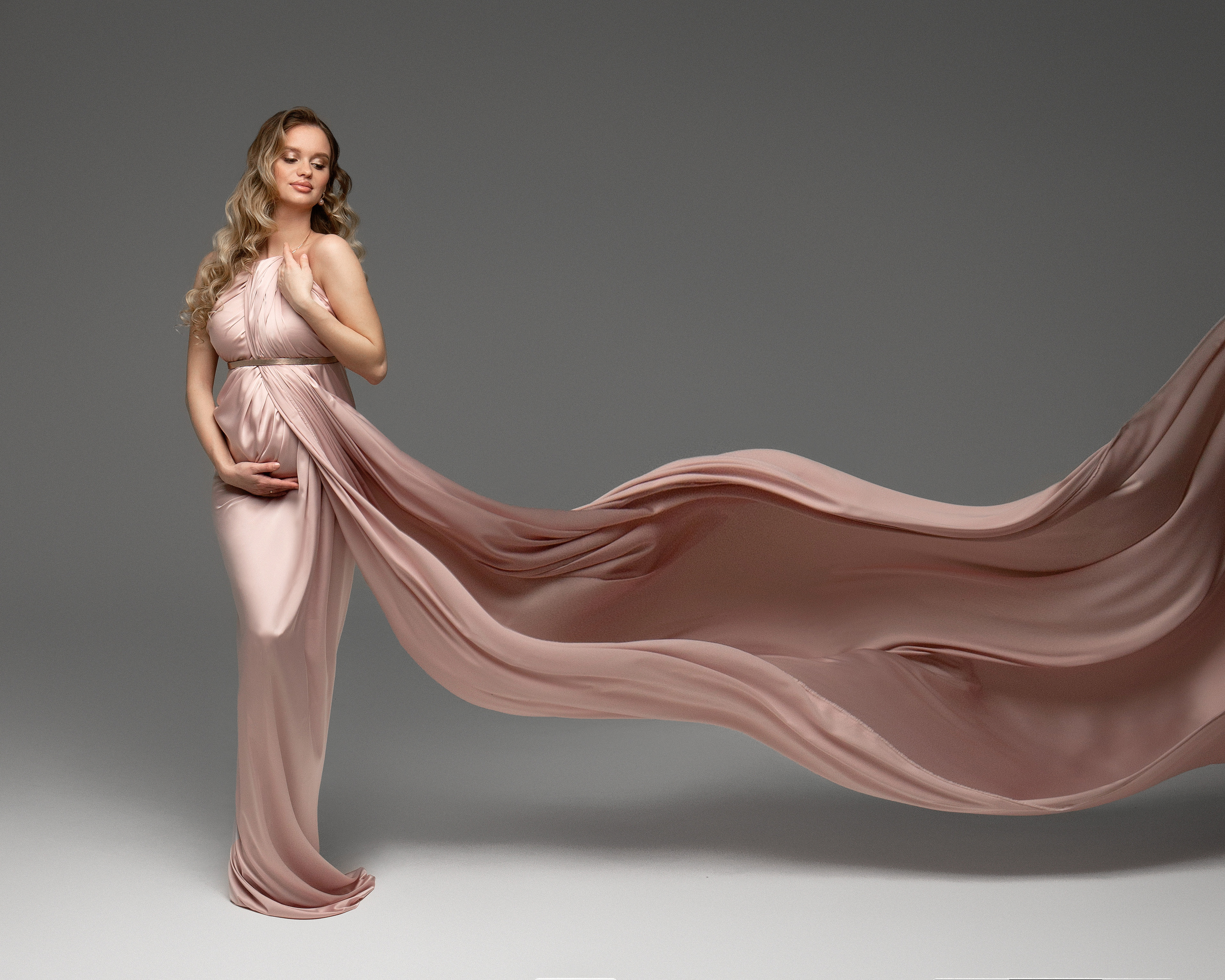 Беременная девушка в розовой летящей ткани
