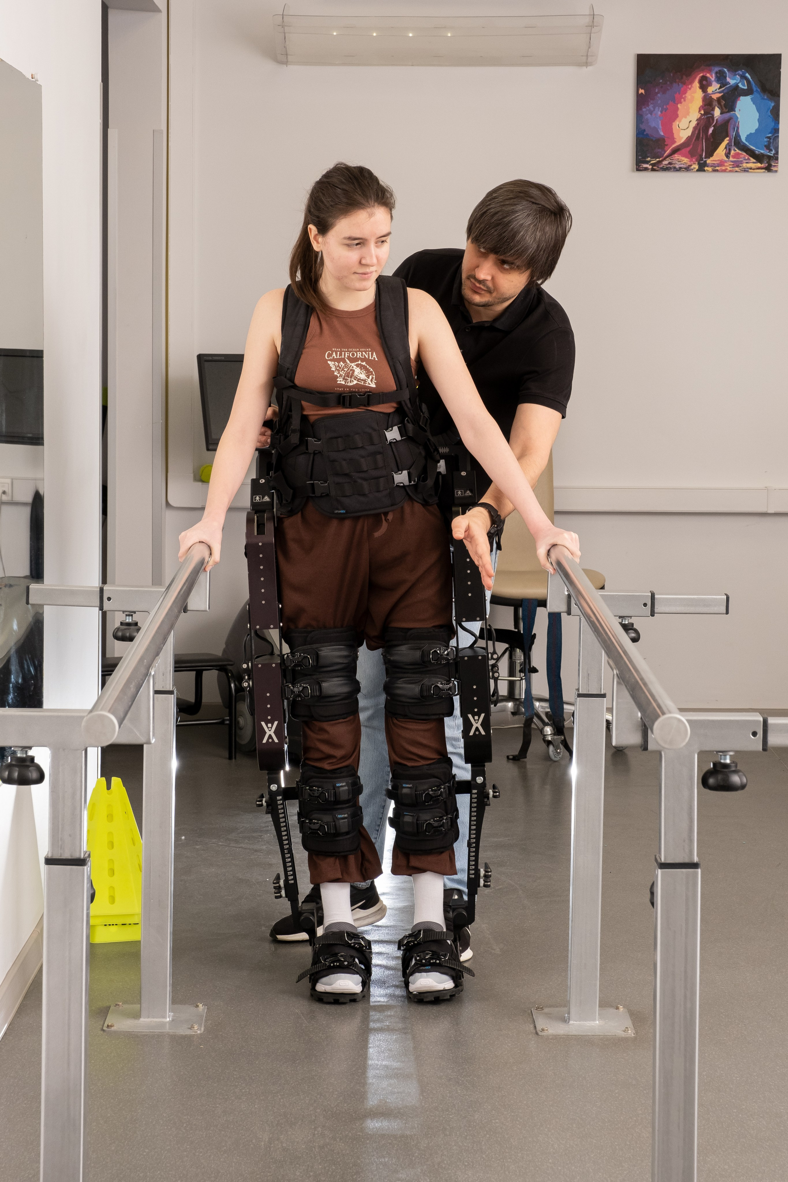 Доктор помогает делать первые шаги в экзоскилете