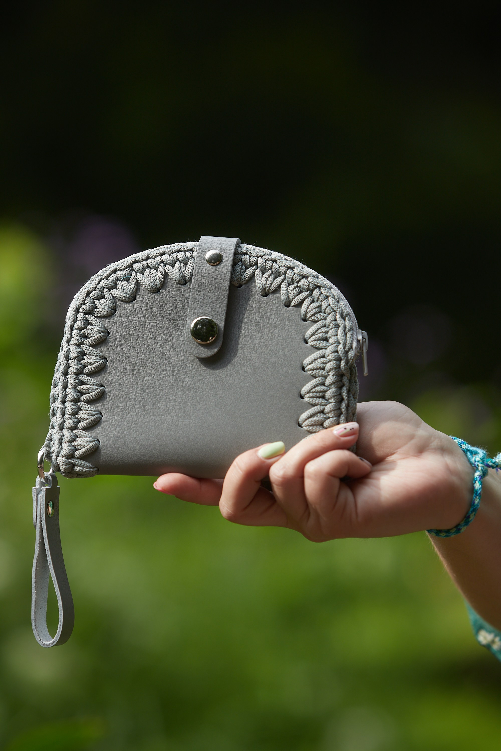 Съёмка серого клатча ручной работы с плетёной отделкой.