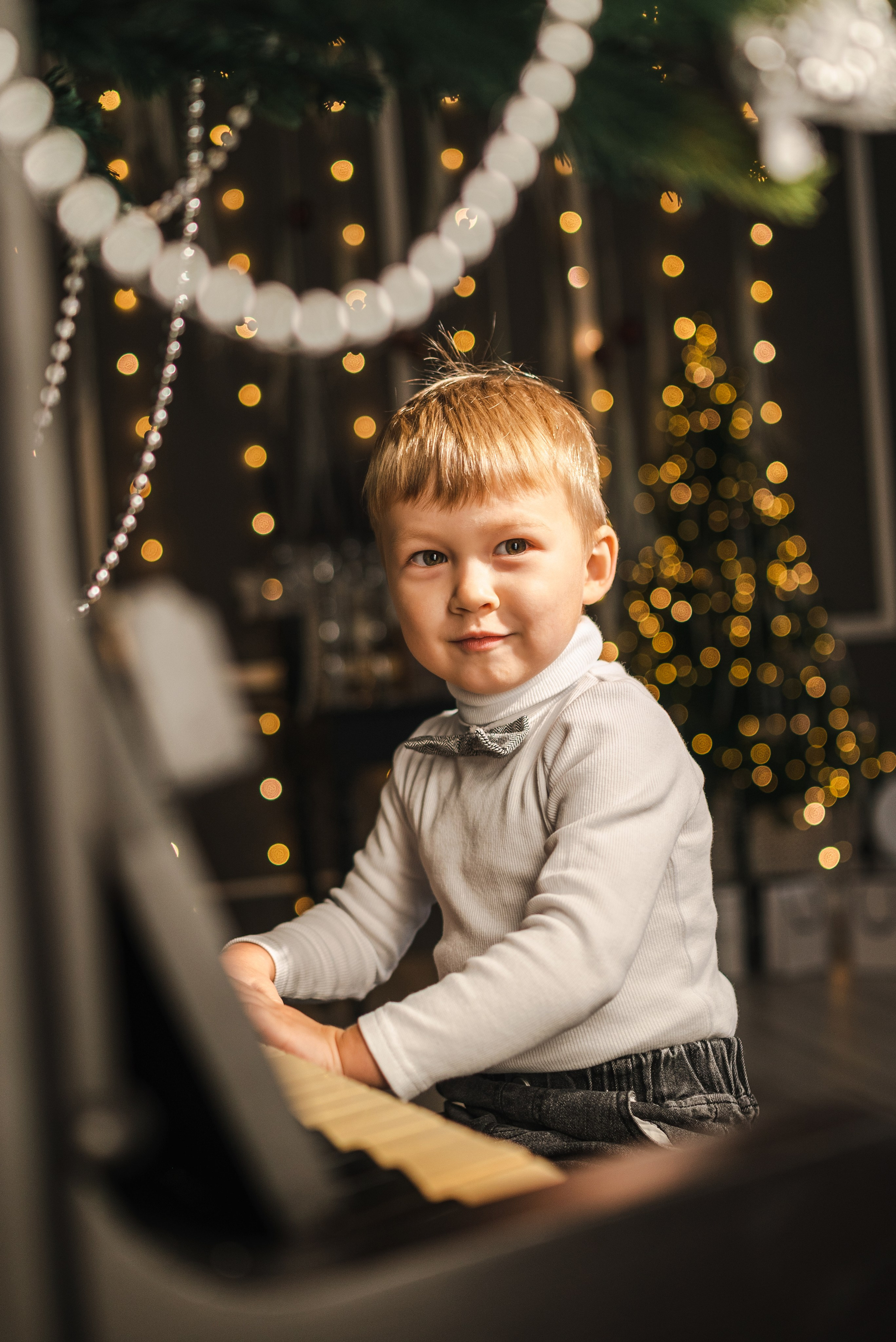 Детская семейная новогодняя фотосессия 2025 в фотостудии в Каменске-Шахтинском и Ростове-на-Дону. Ребенок играет на пианино. Фотограф Ольга Сагал 