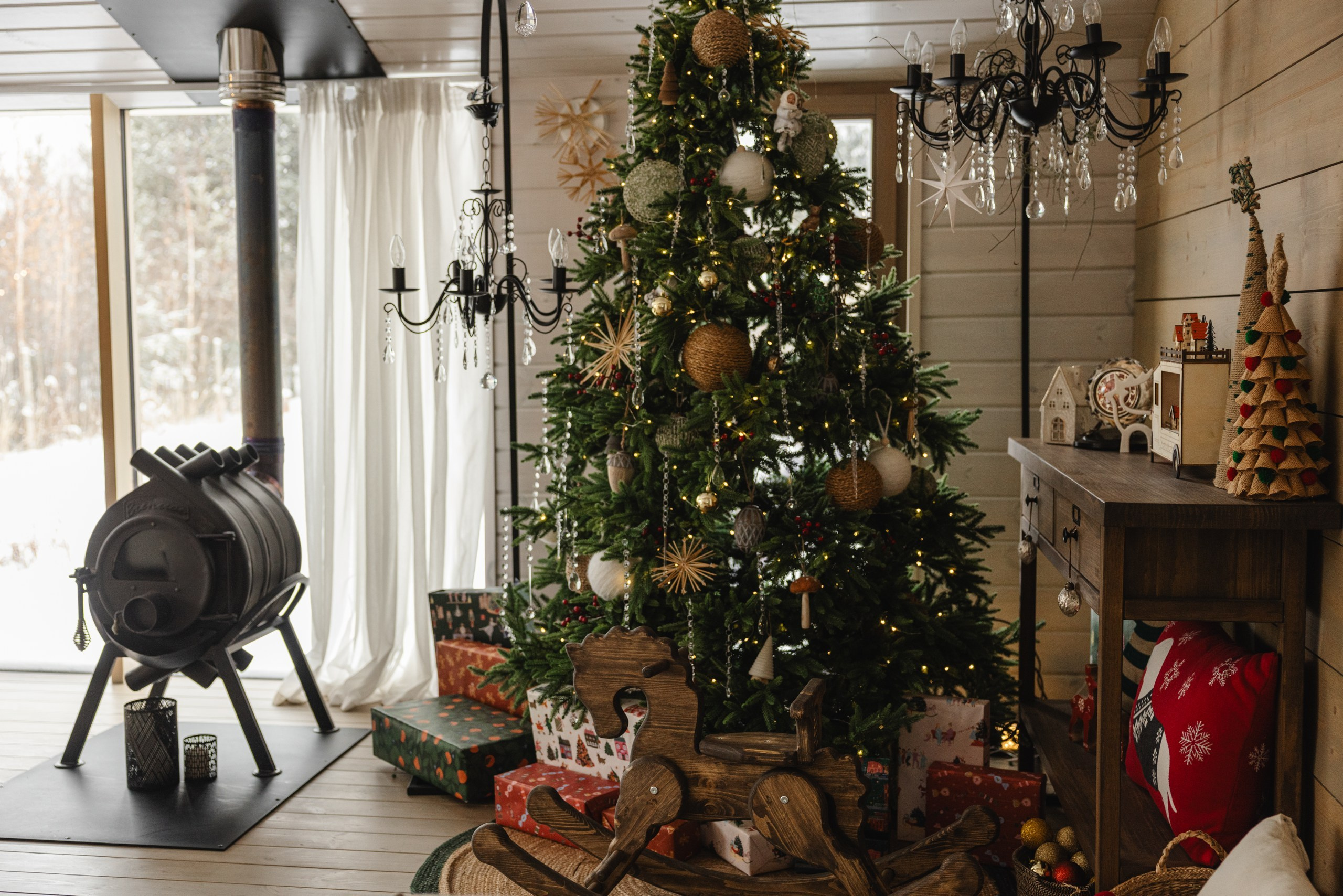 Интерьер загородного дома 'Панорама': просторная гостиная с большой зелёной ёлкой, сверкающие гирлянды и семейные фотографии