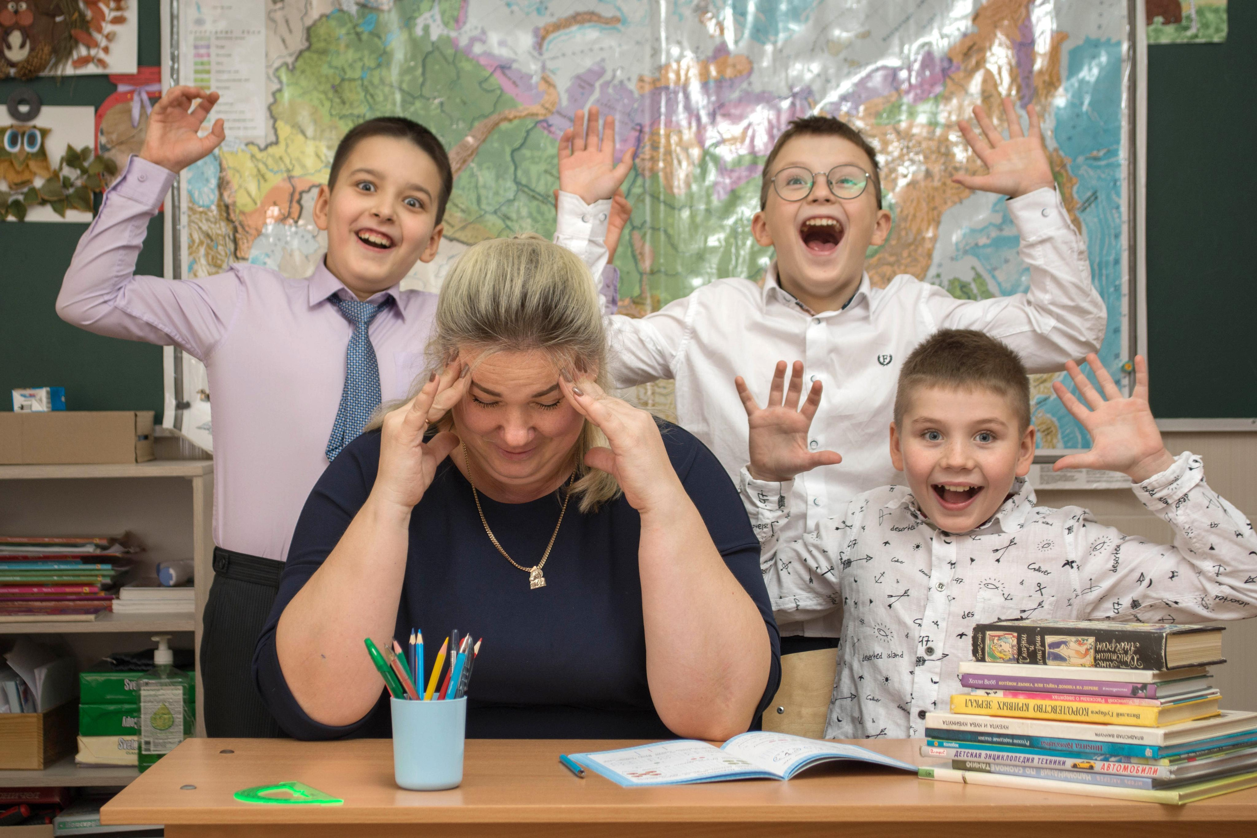 Уставший учитель с учениками фотография в классе.