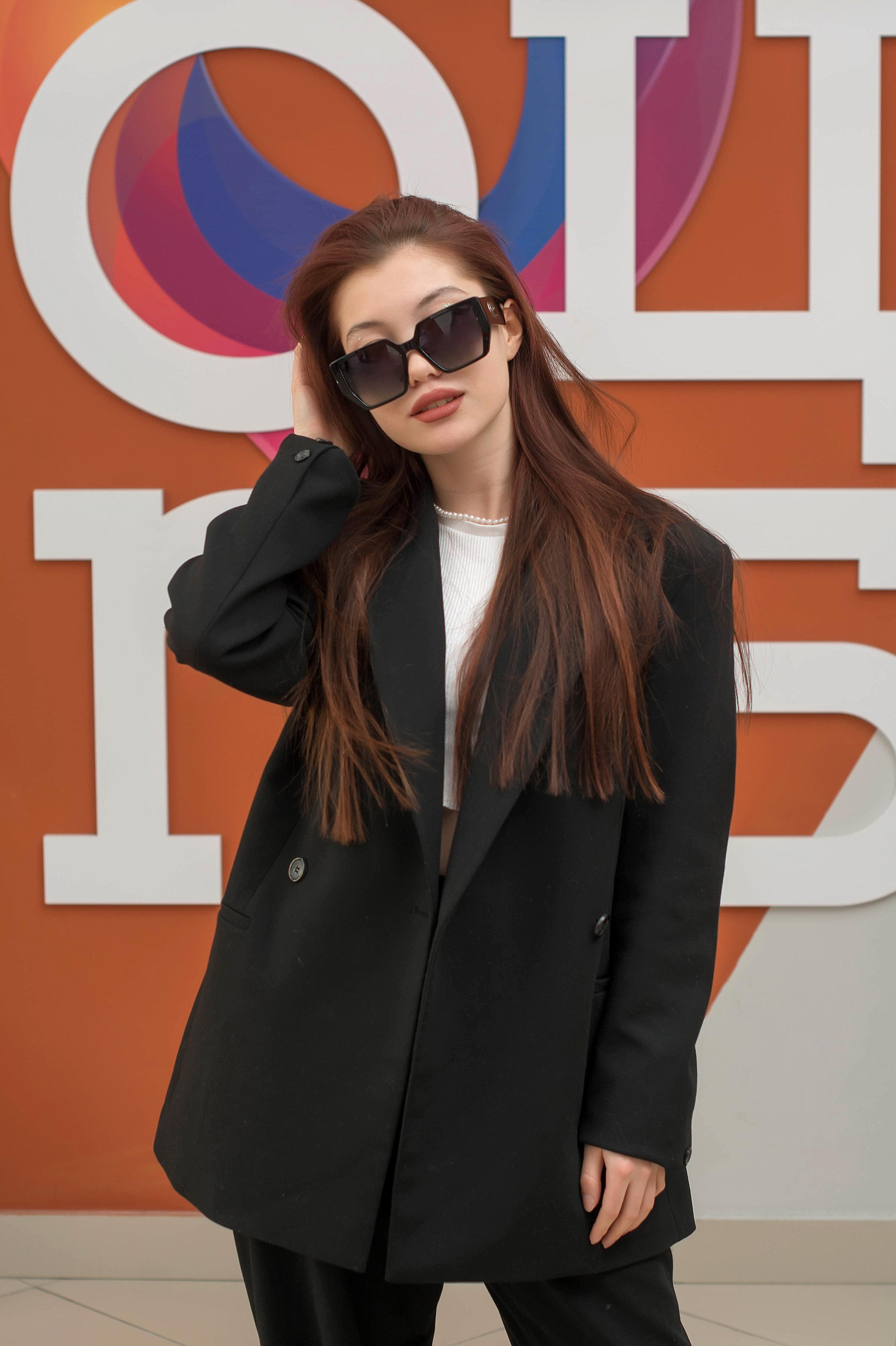 Стильная девочка в чёрных очках на фоне любимой школы.