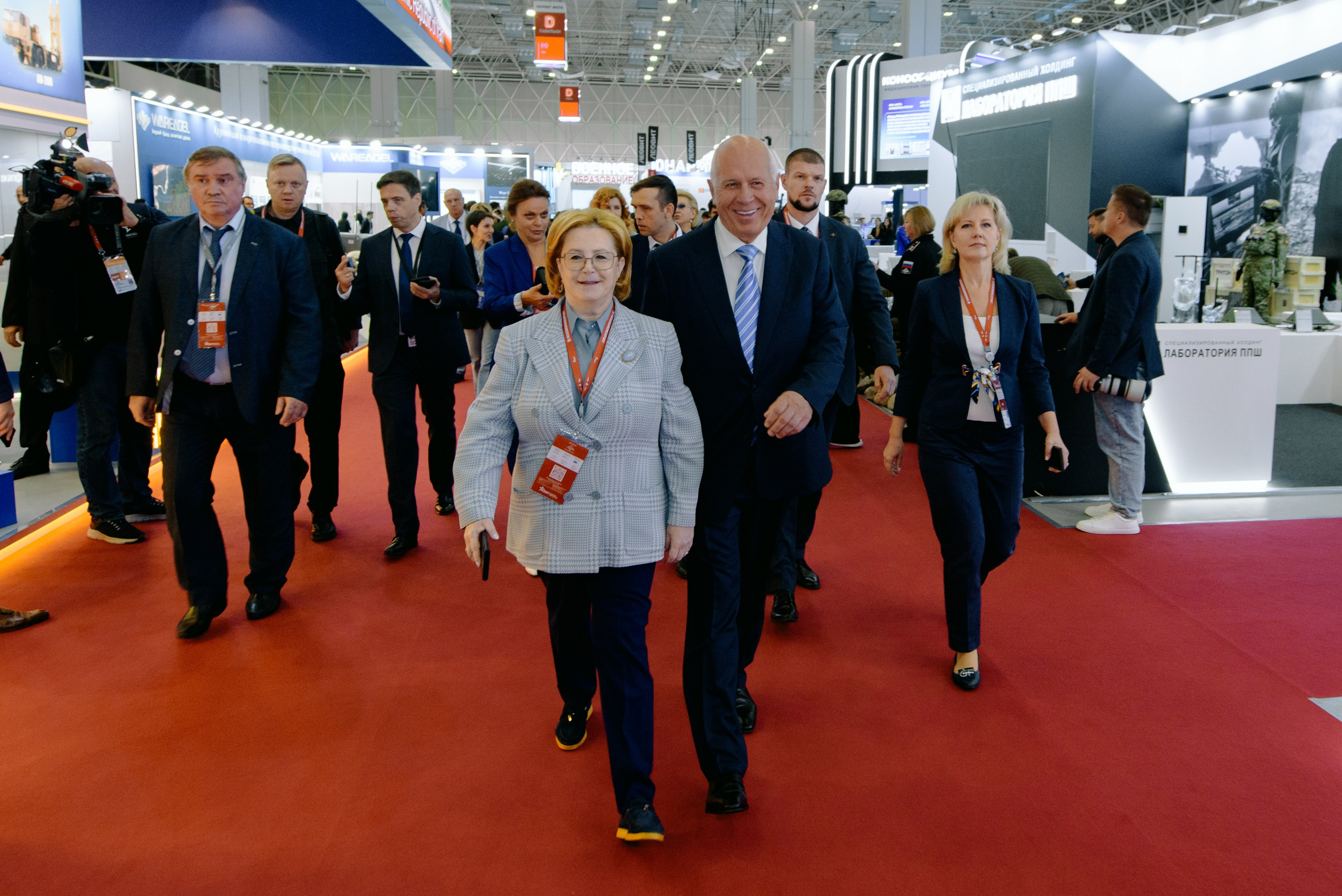 Фотография с выставки, на которой изображены участники, обсуждающие экспонаты.  Фотография репортажного характера, запечатлевшая важный момент корпоративного мероприятия. Министр обороны РФ Белоусов. Чемезов Роснано. Армия 2024. Вероника Скворцова